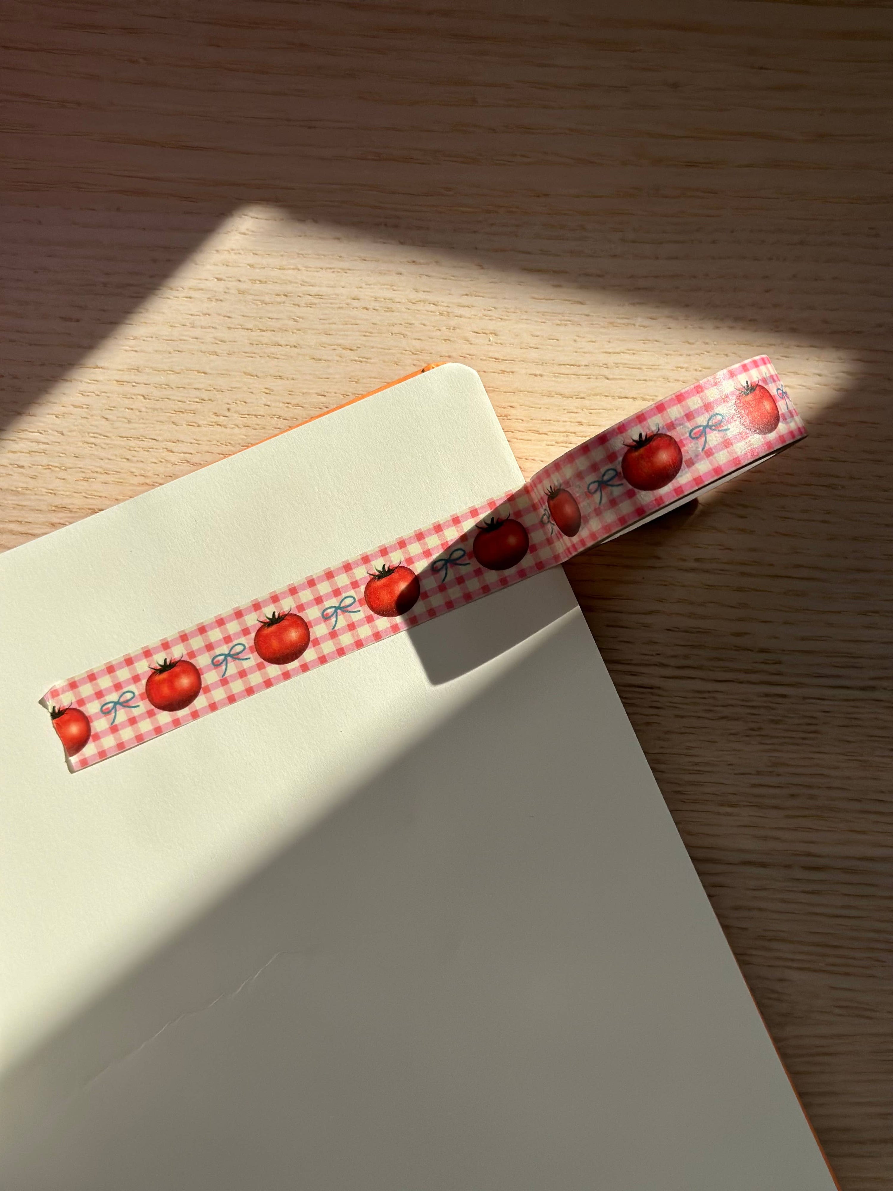 Notebook with a decorative ribbon featuring red apples on a wooden surface