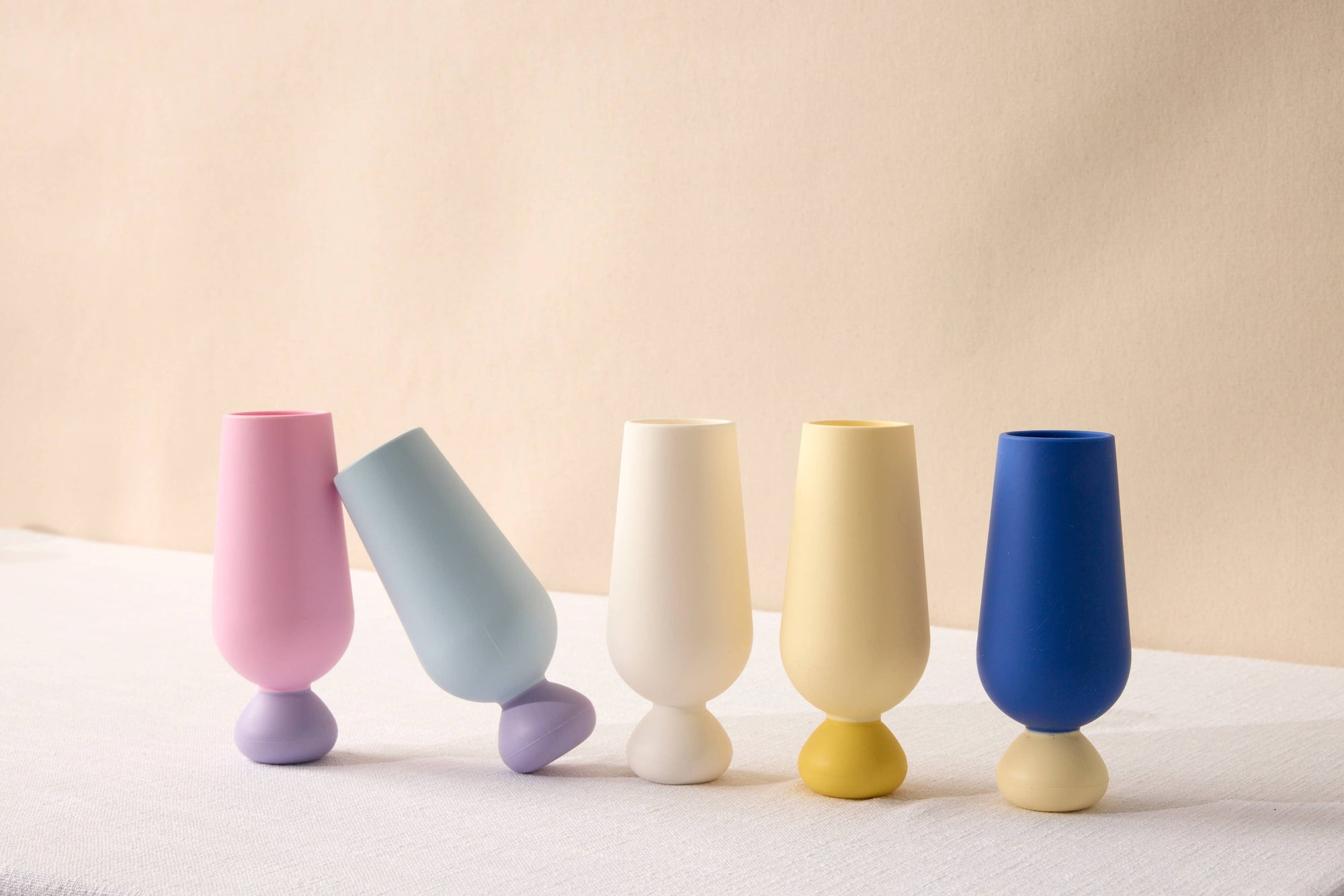 Set of colorful silicone cups on a light surface with a beige background