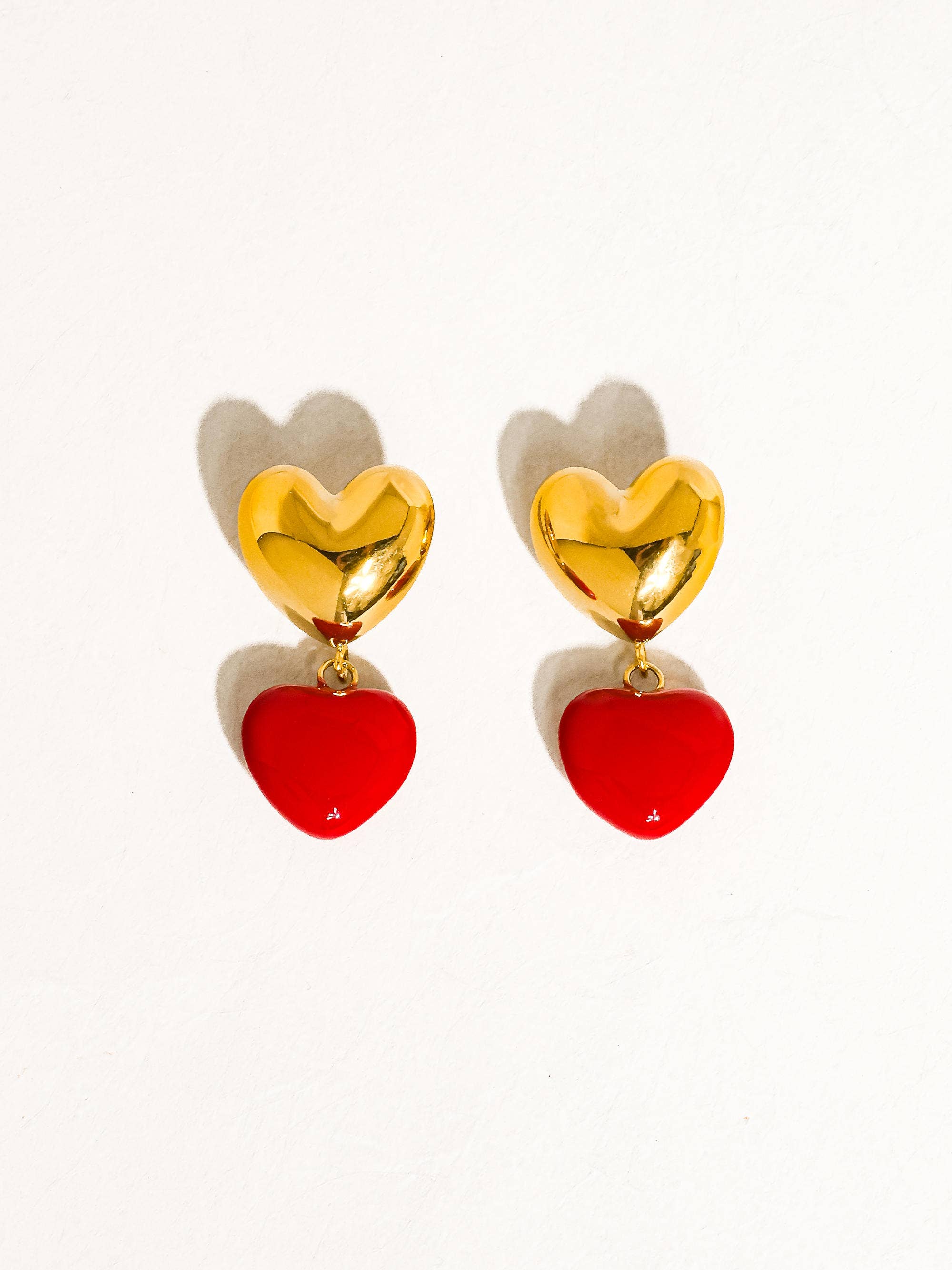 Heart-shaped earrings with gold and red hearts on a white background