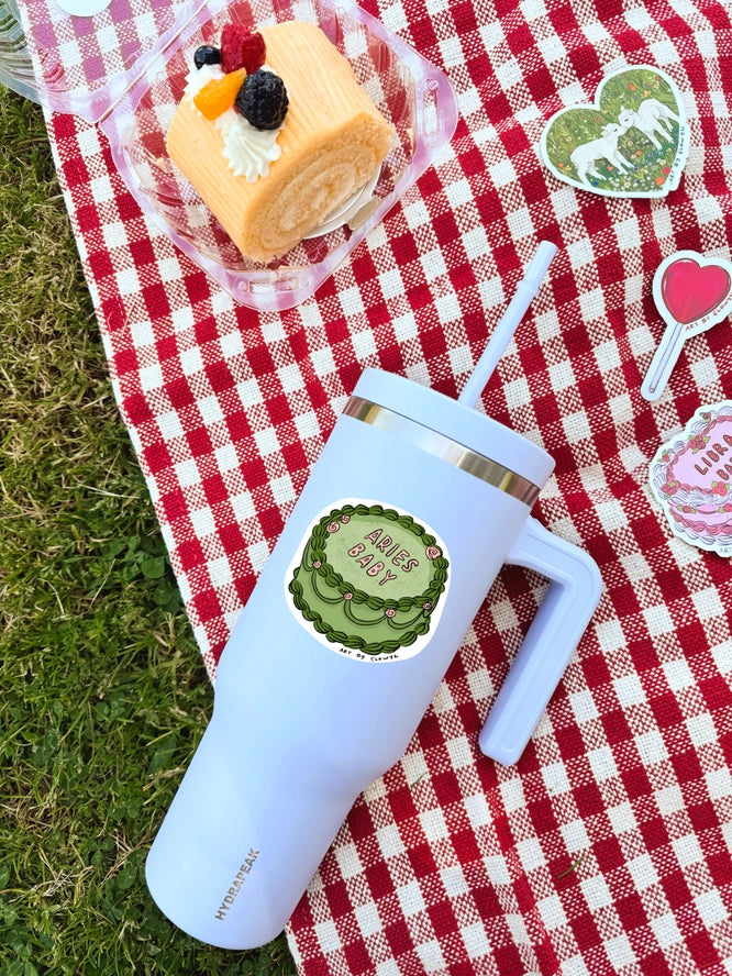 White insulated tumbler with a sticker on a red and white checkered tablecloth with a dessert.