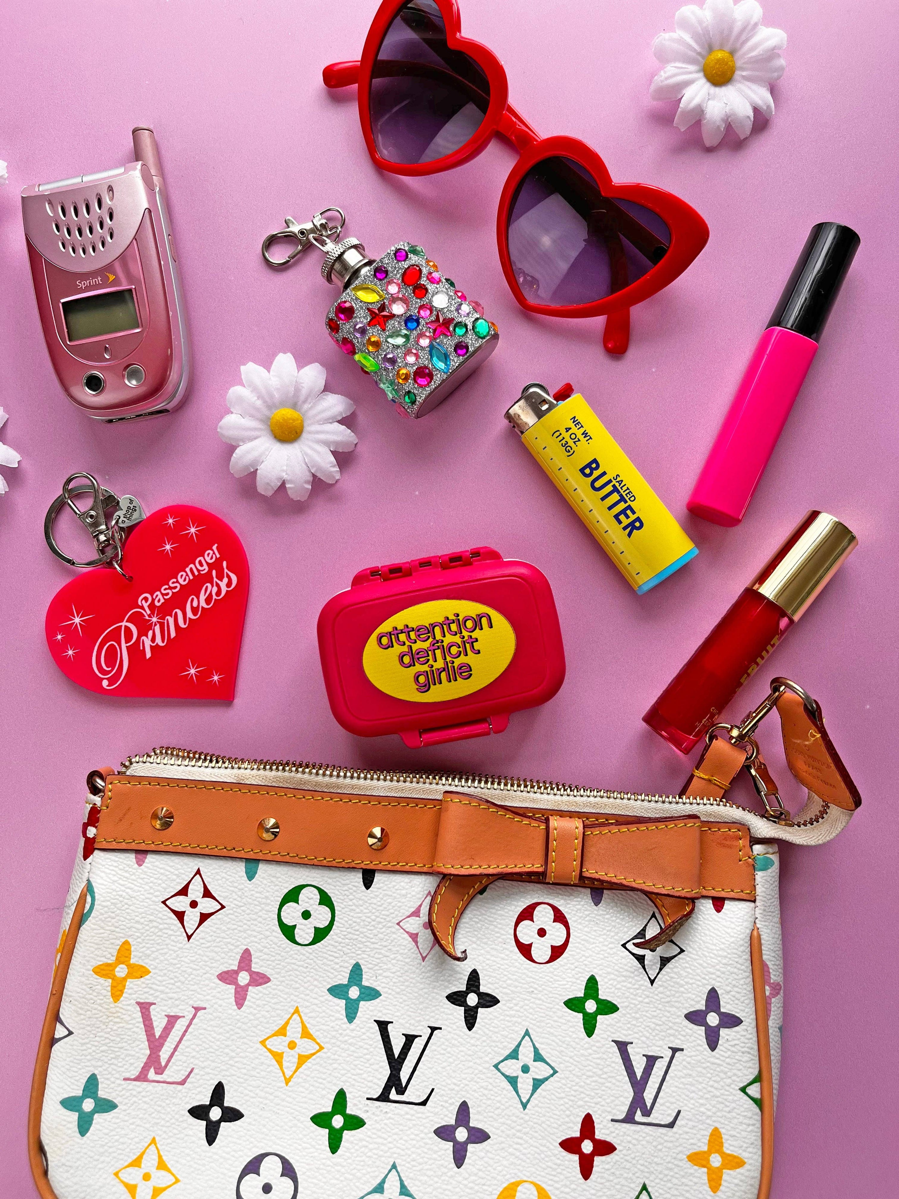Collection of colorful items including a handbag, lip products, and accessories on a pink background