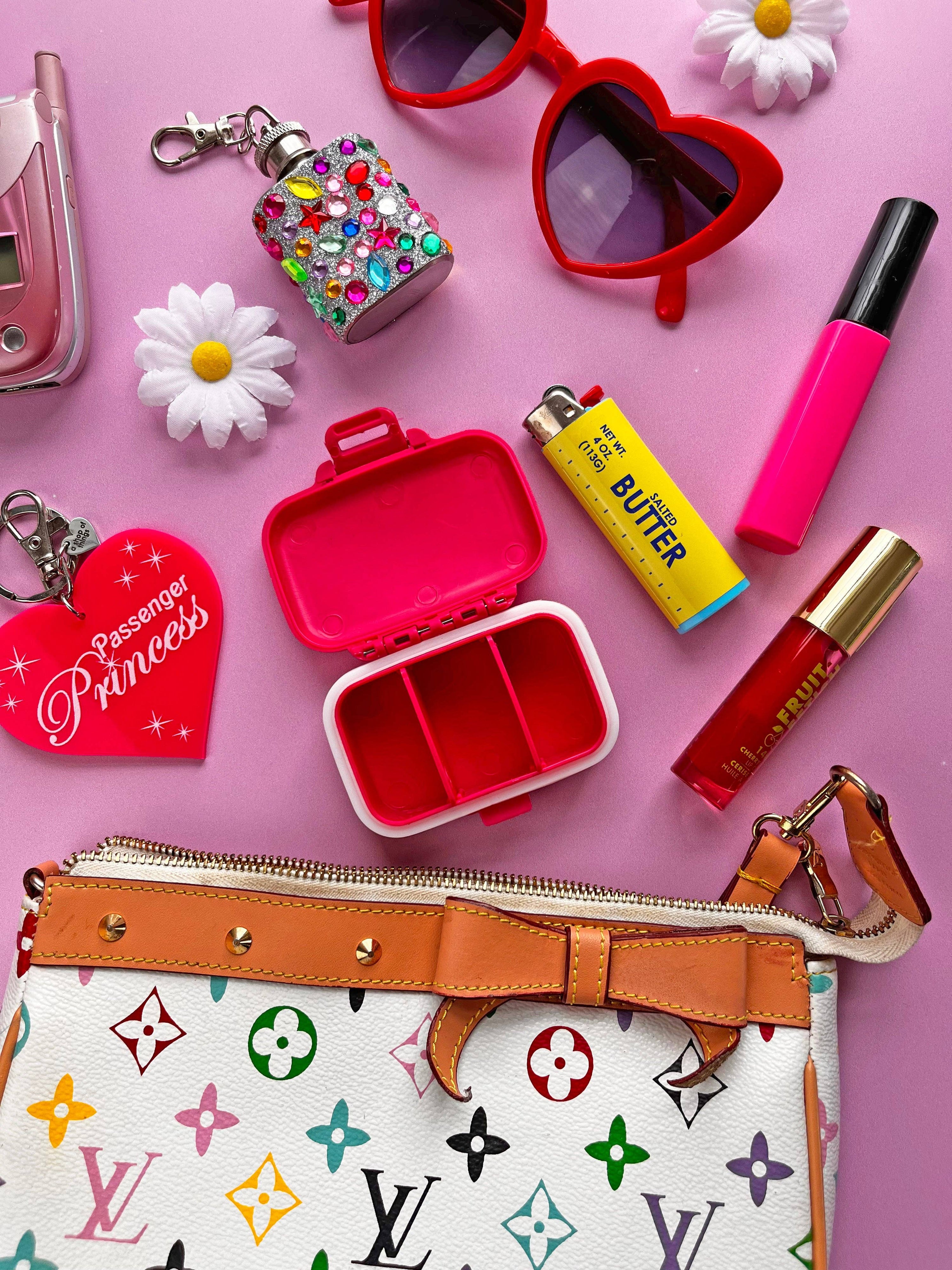 Collection of colorful items including a purse, lip gloss, and keychain on a pink background