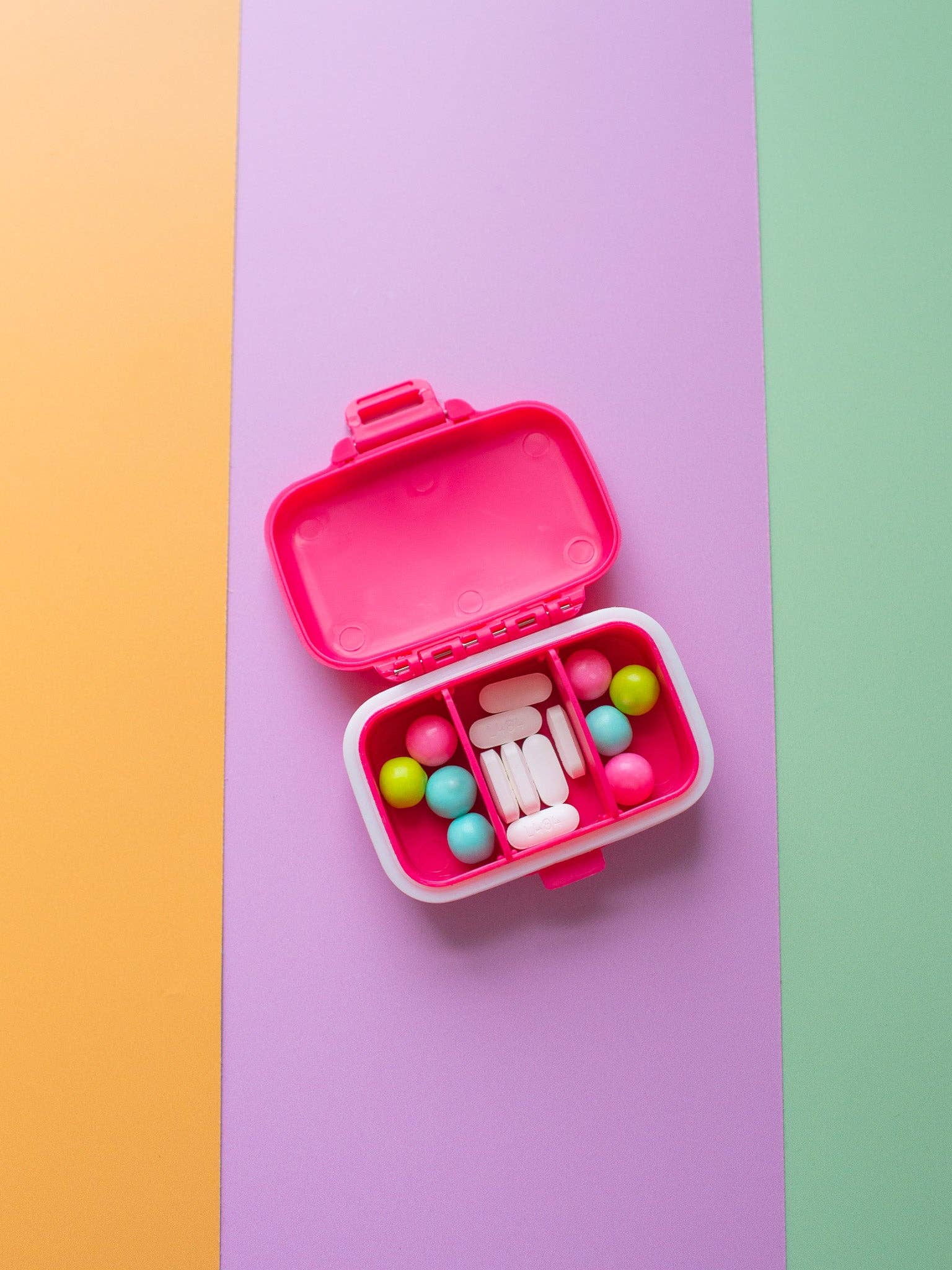 Pink bento box with colorful compartments on a multicolored background