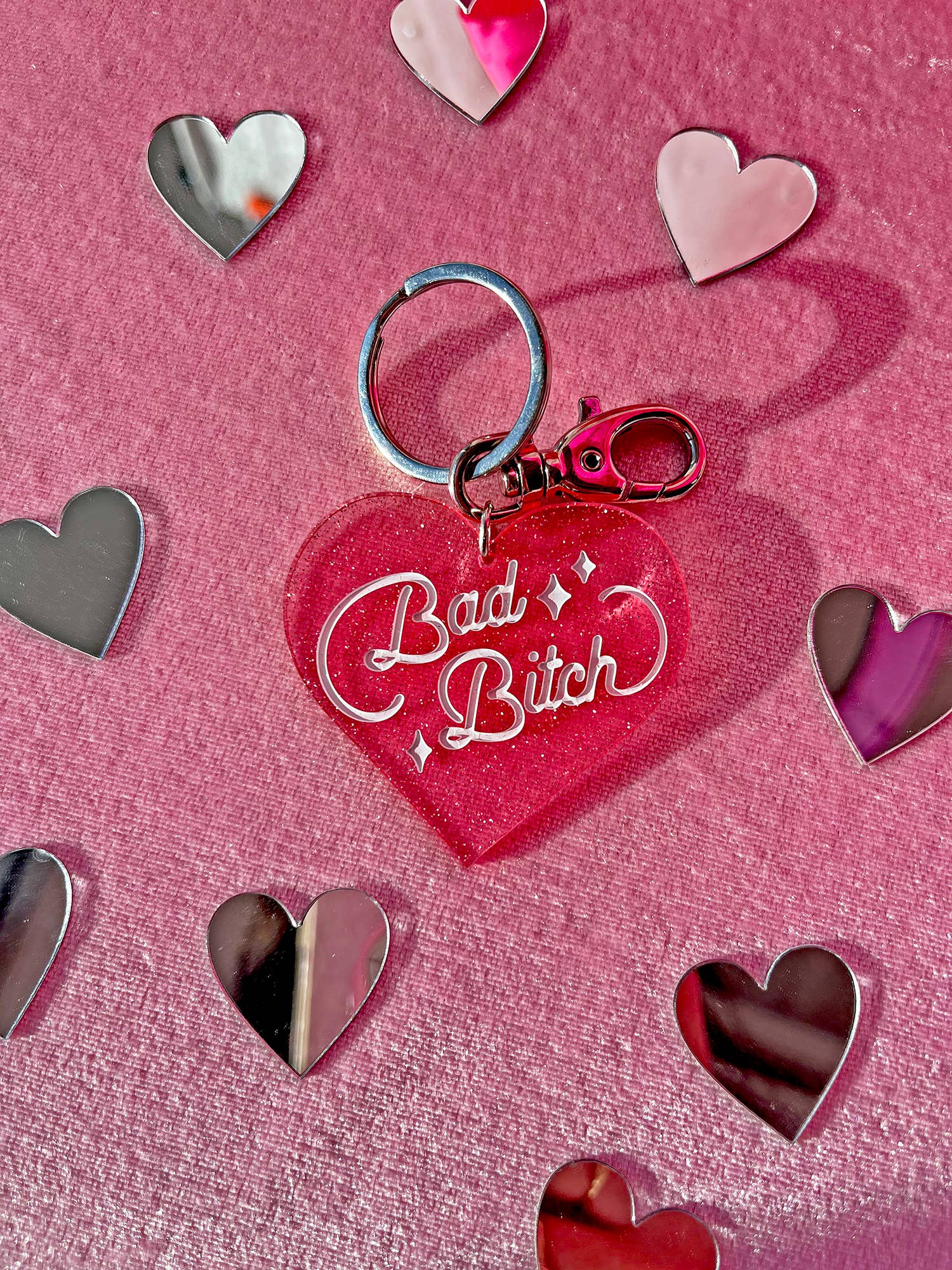 Heart-shaped keychain with 'Bad Bitch' text on a pink background with heart decorations