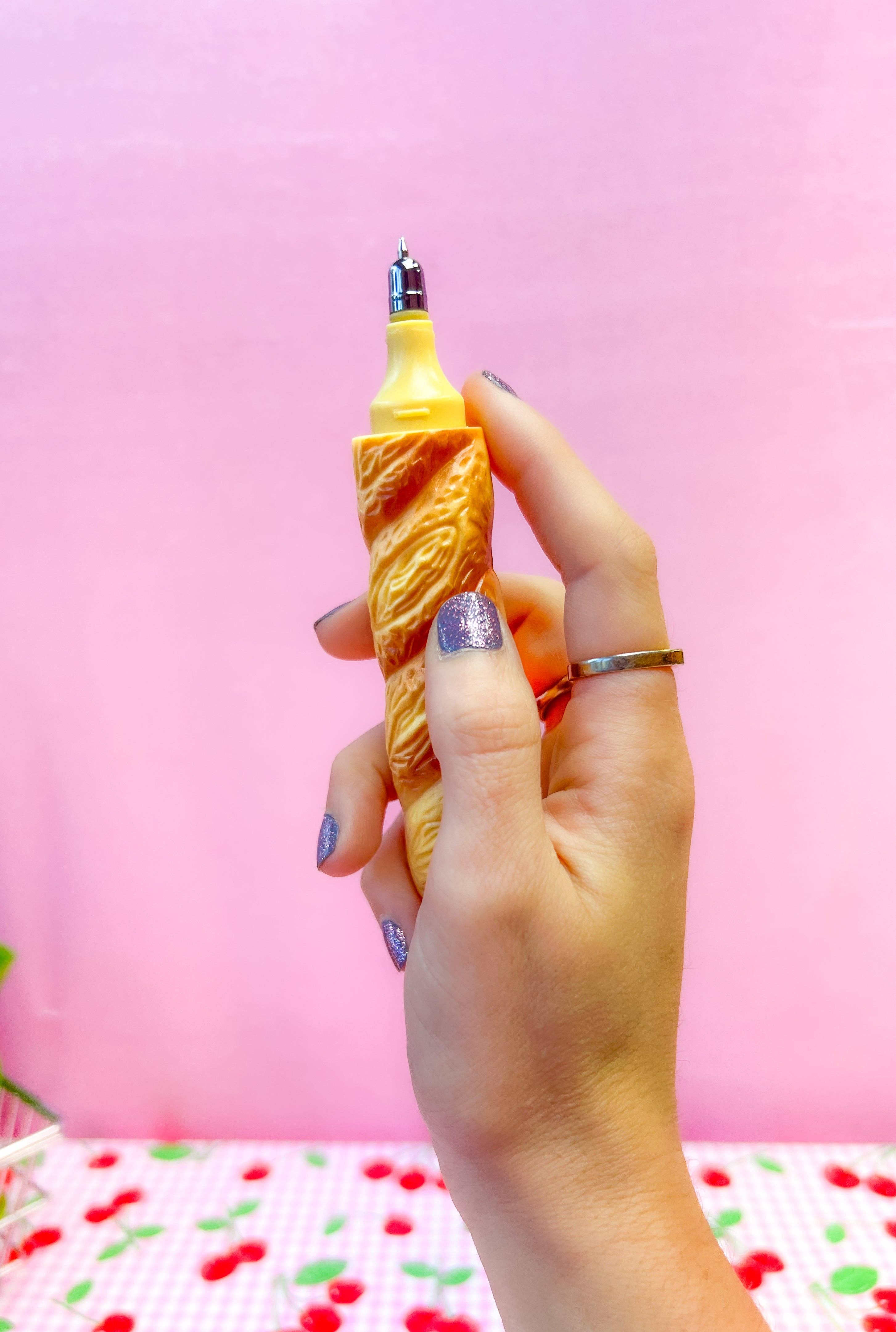 Hand holding a novelty light bulb with a decorative base against a pink background