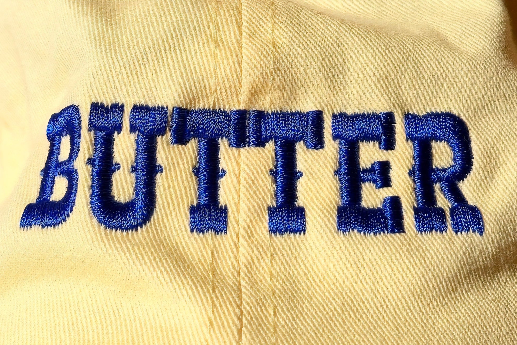 Beige fabric with 'BUTTER' embroidered in blue letters