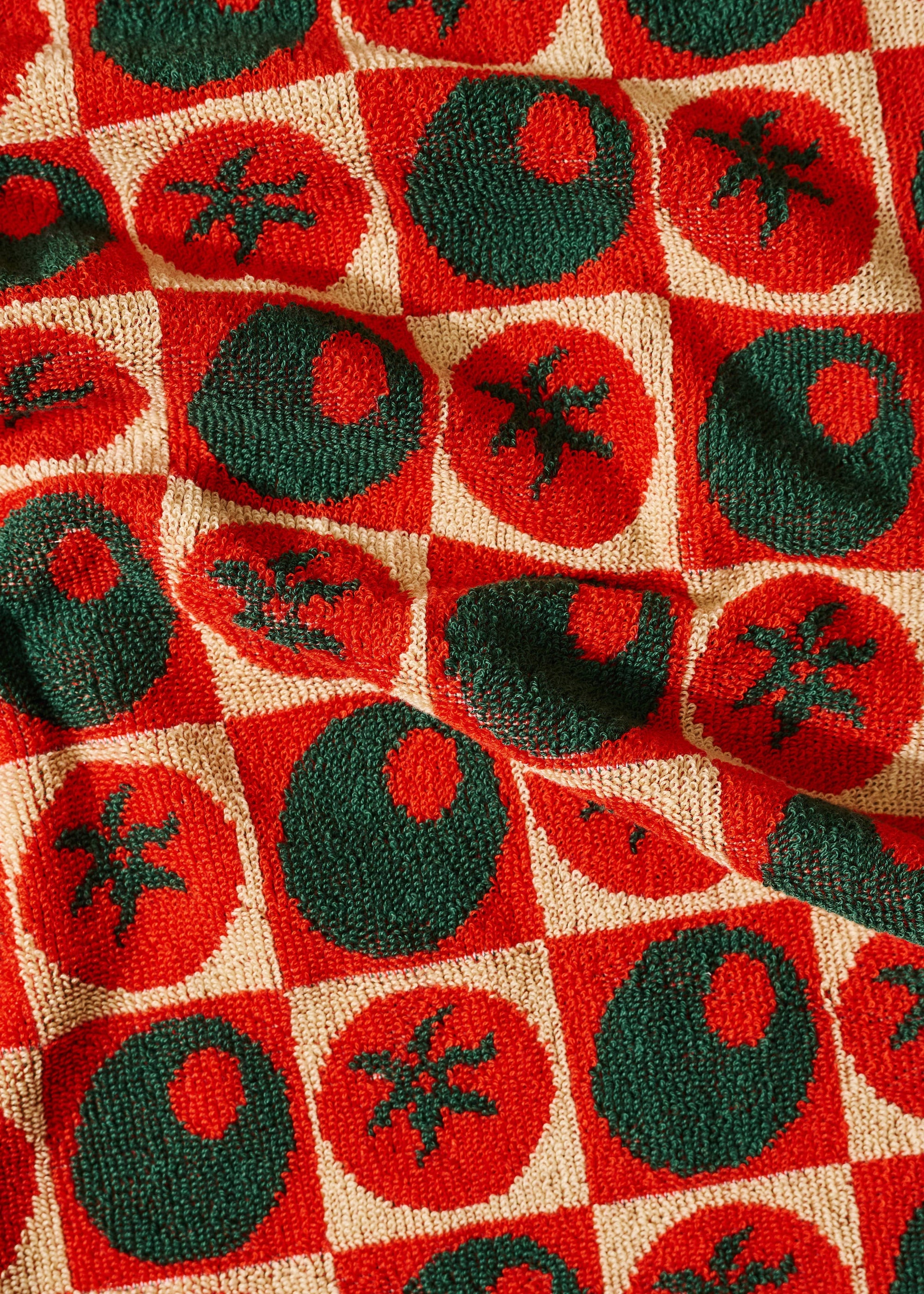 Patterned fabric with red and green shapes on a checkered background