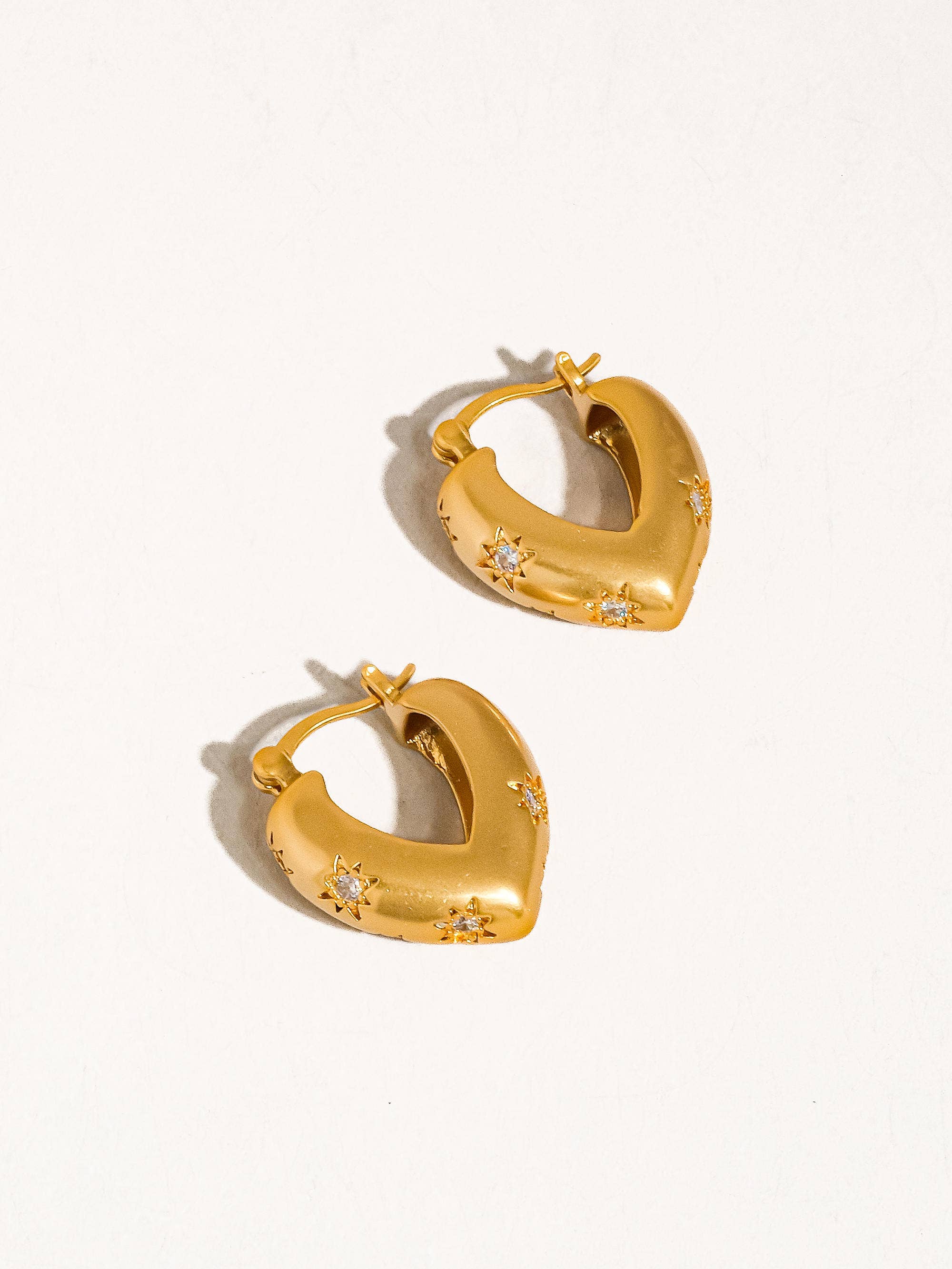 Gold hoop earrings with star-like embellishments on a white background