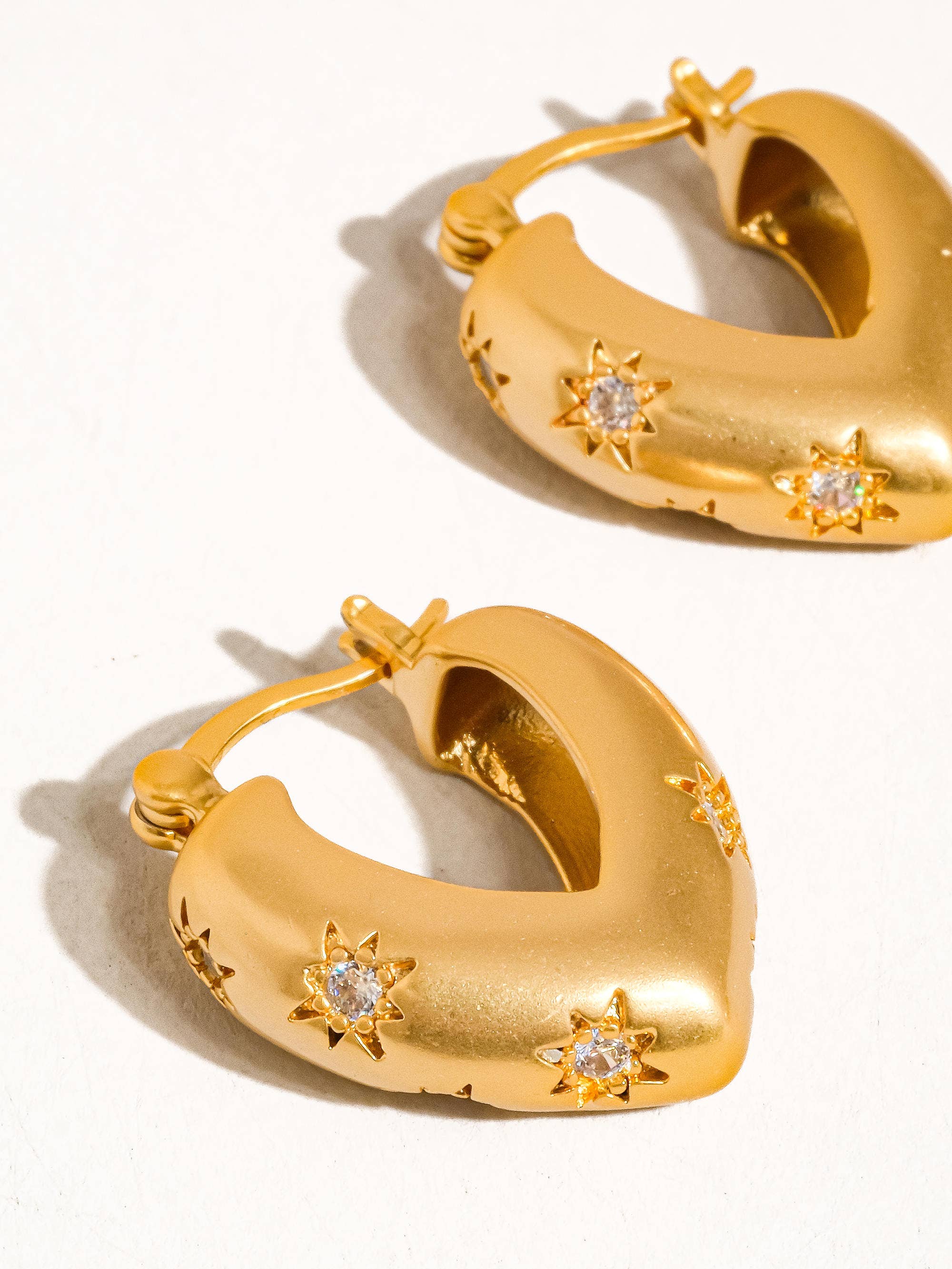 Gold hoop earrings with star designs on a white background