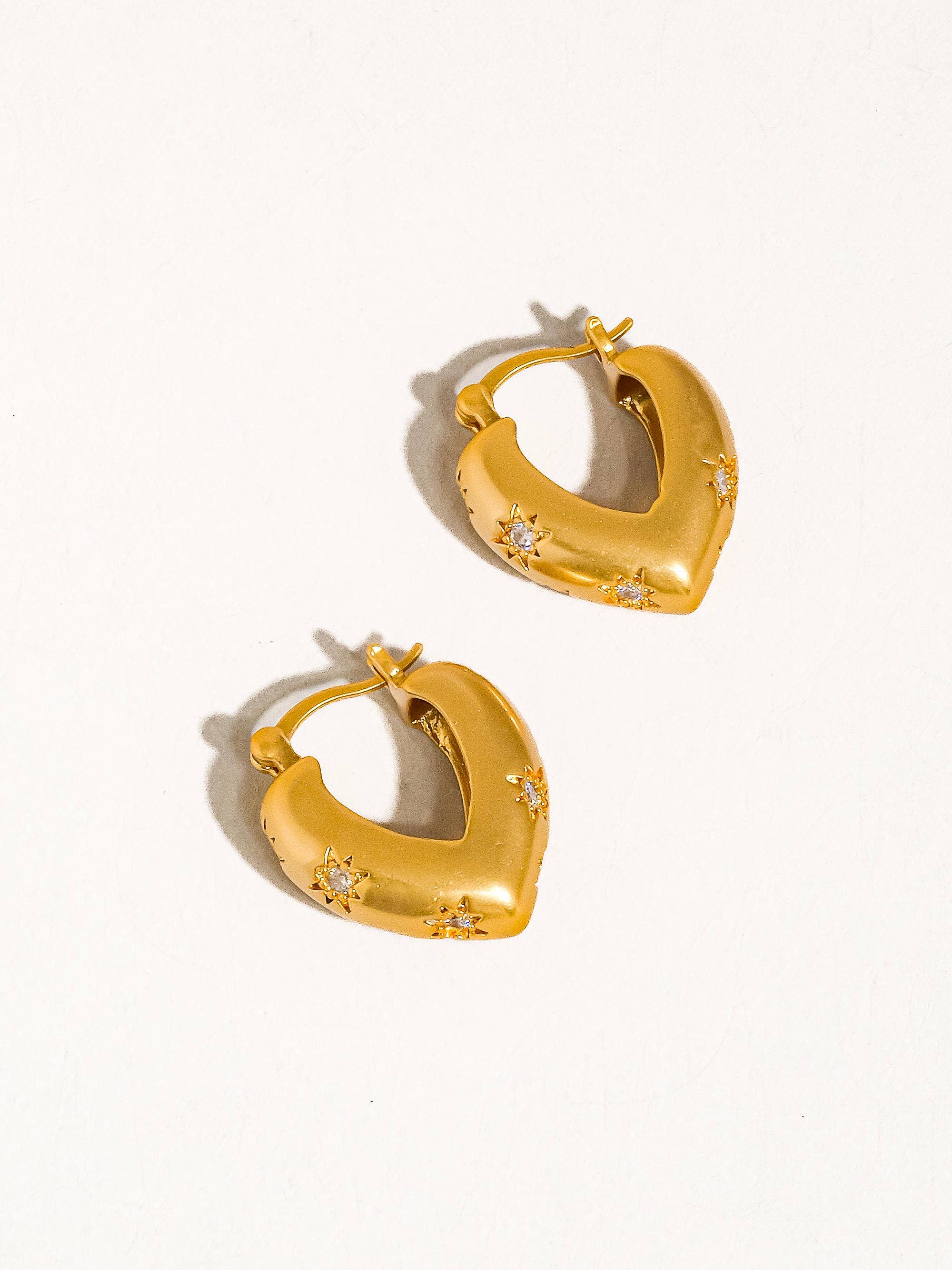 Gold hoop earrings with small diamonds on a white background