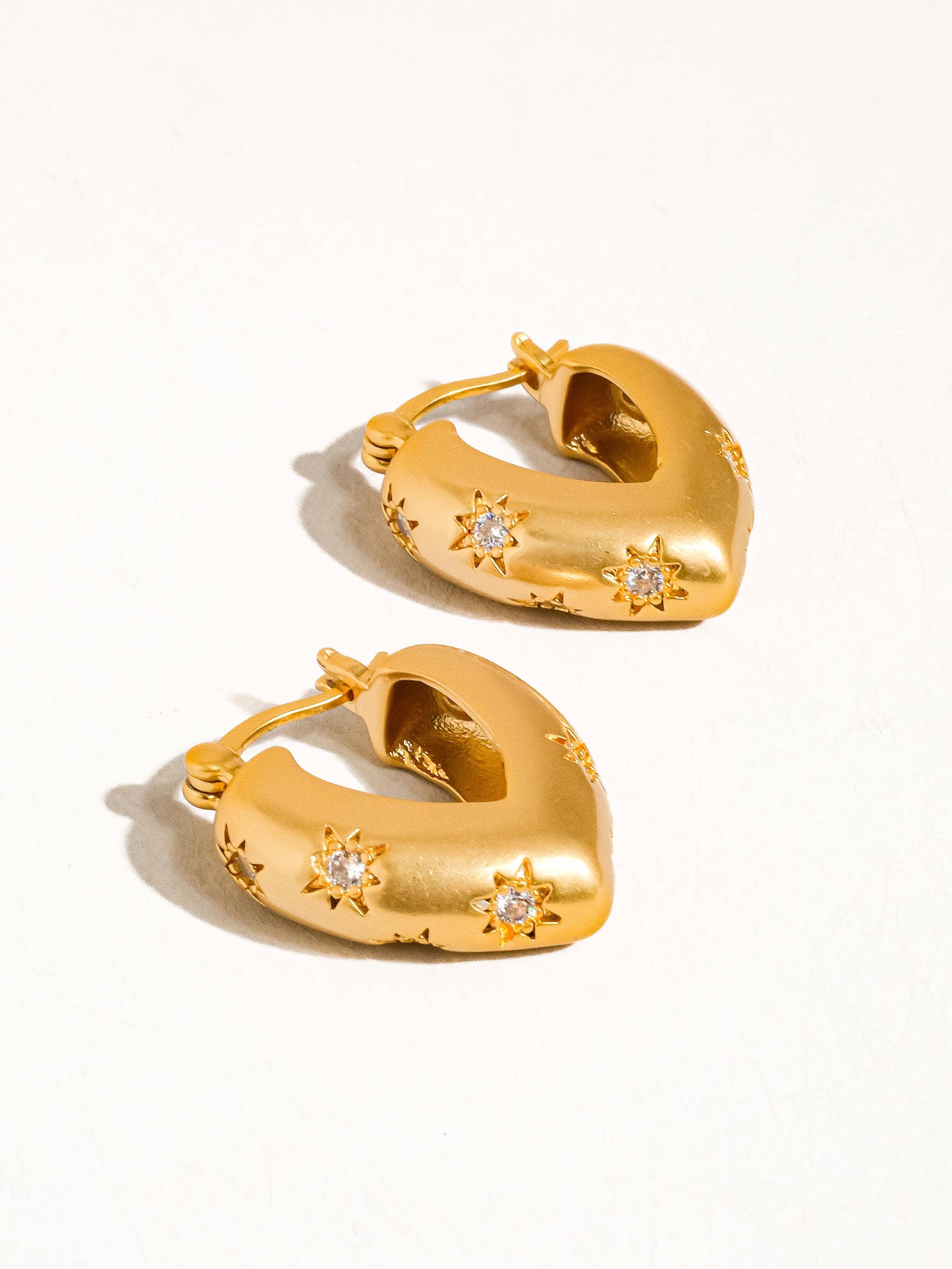 Gold hoop earrings with star designs on a white background