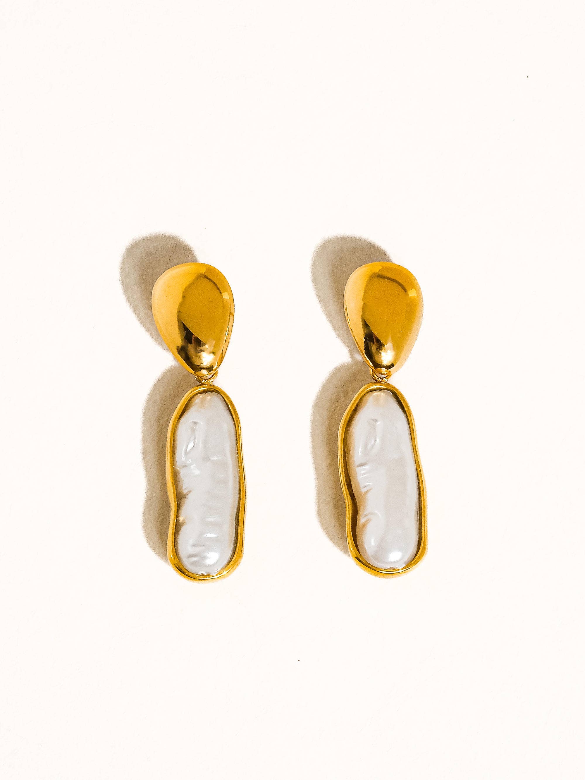 Gold earrings with white stone on a white background