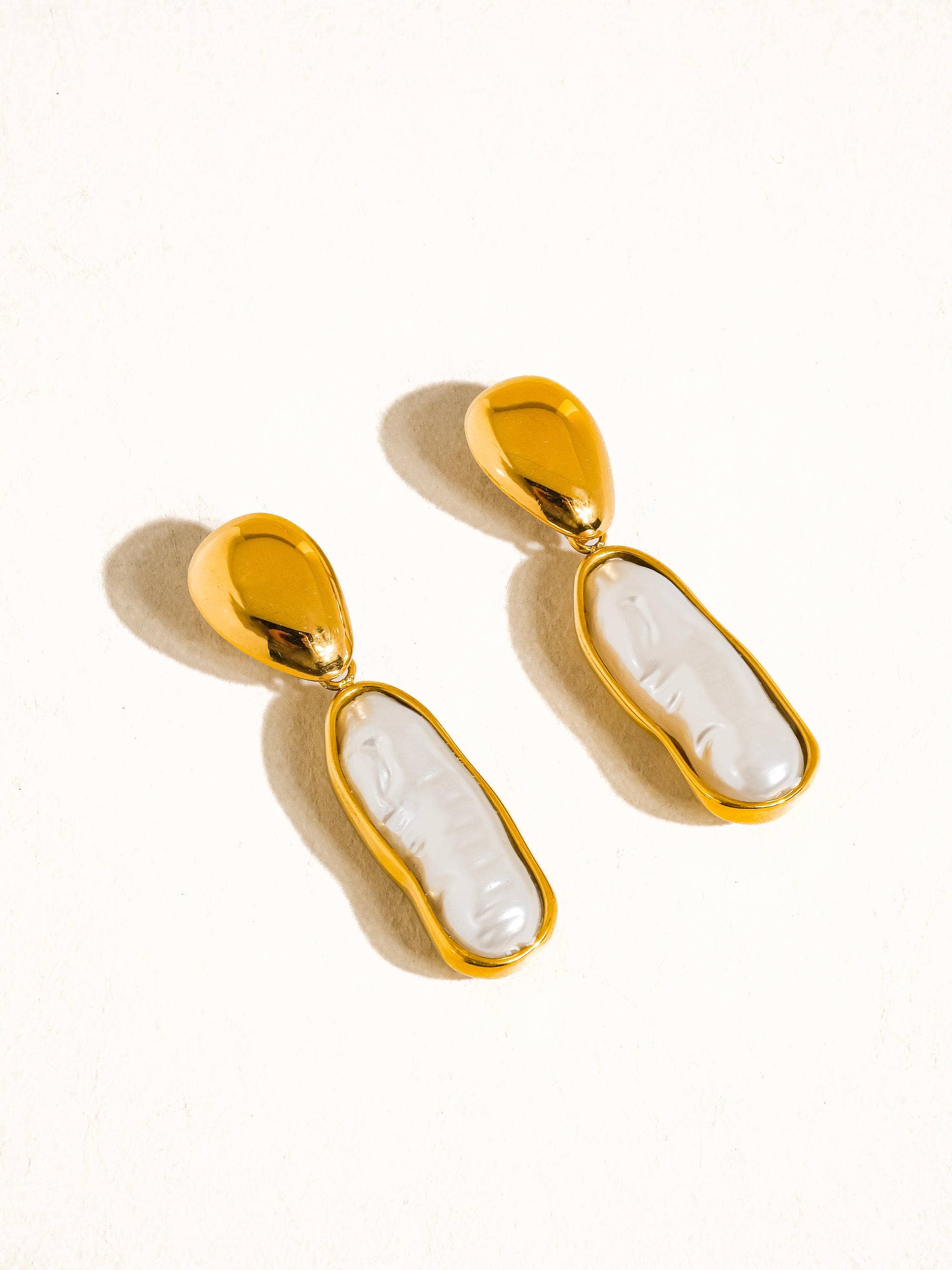 Gold earrings with white stone on a white background
