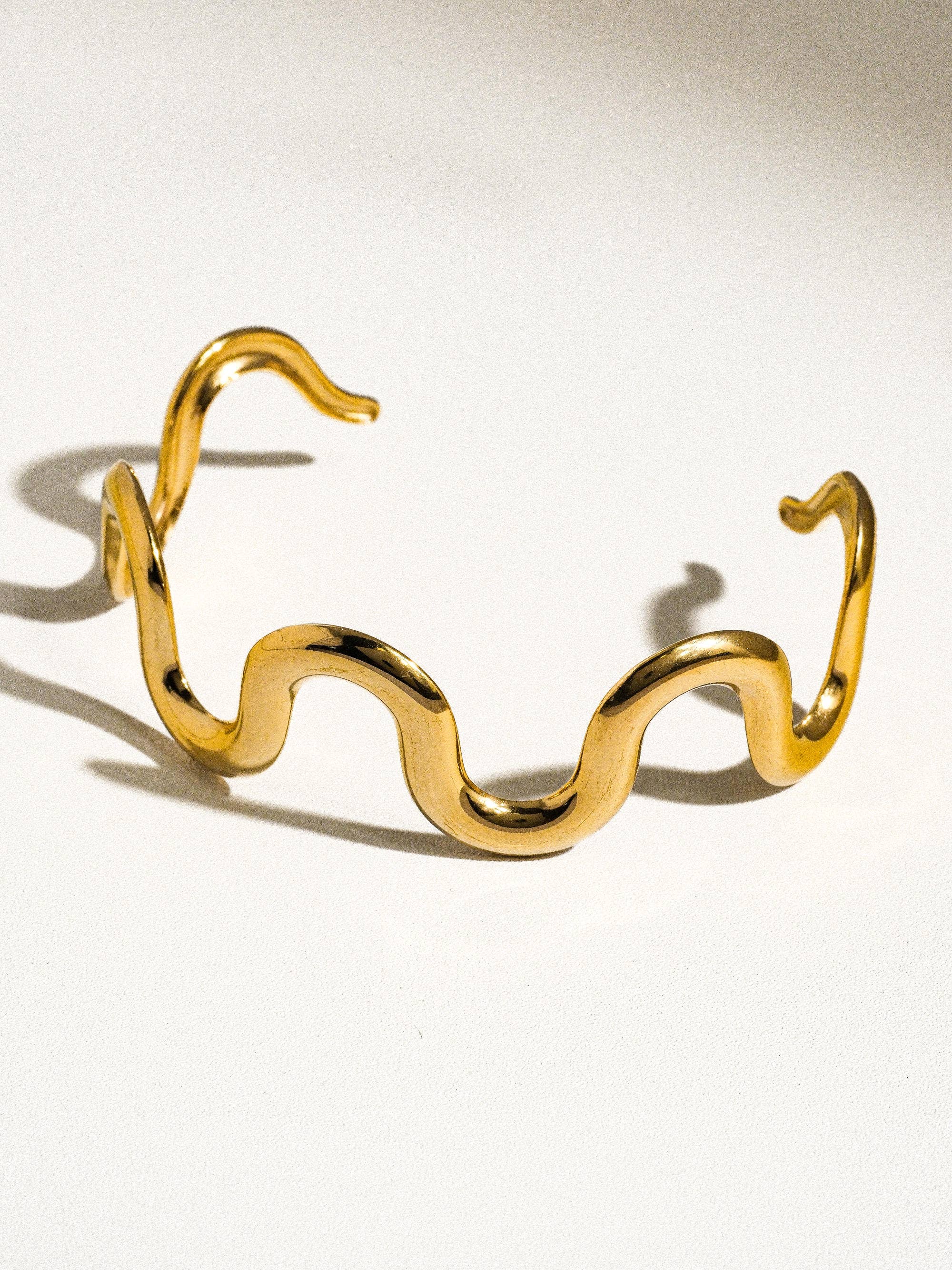 Gold snake-shaped bracelet on a white background