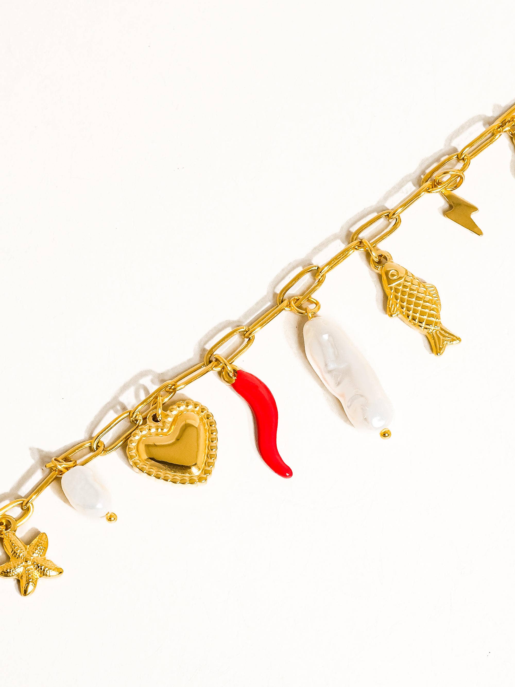 Gold bracelet with various charms on a white background