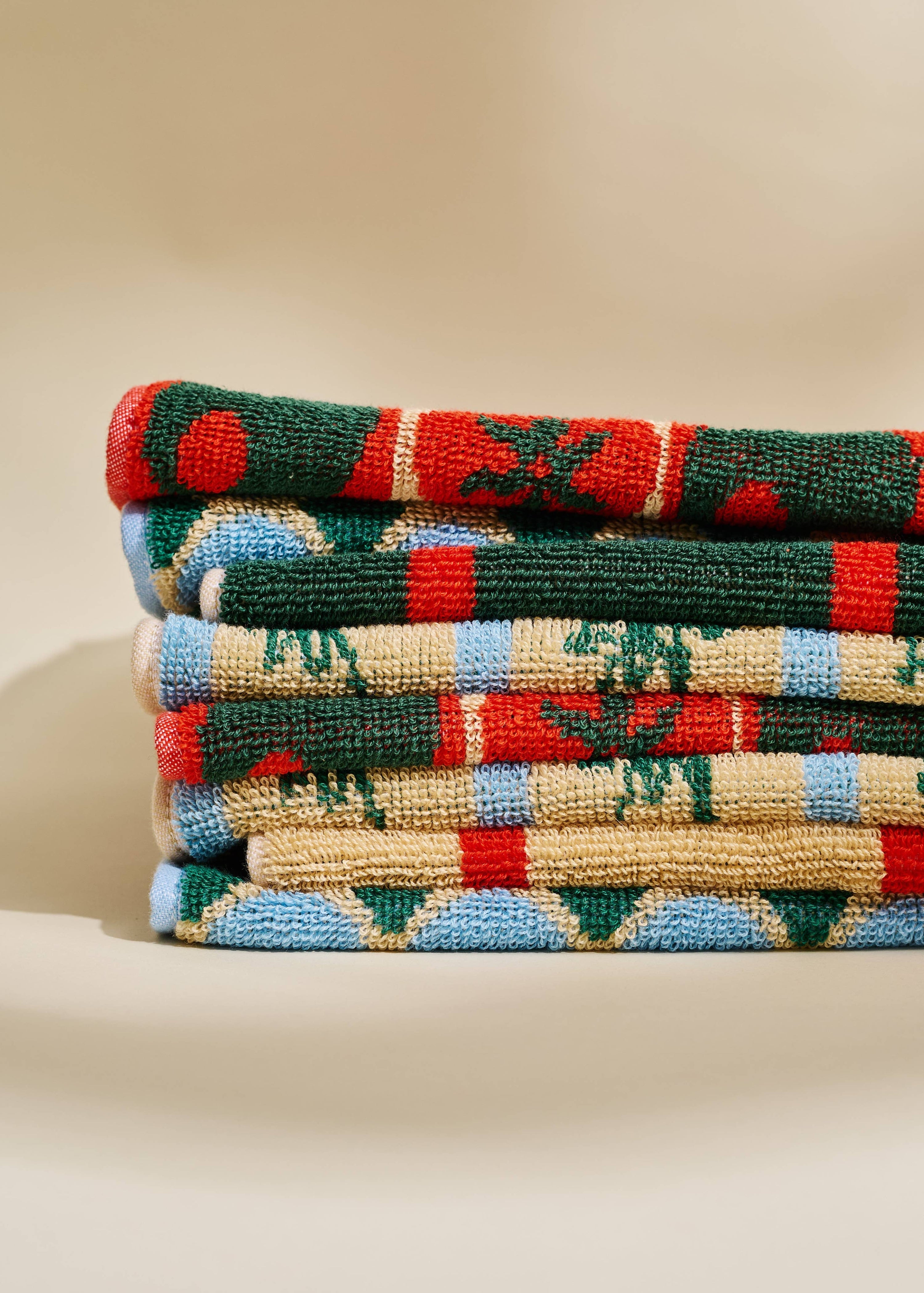 Stack of colorful patterned towels on a beige surface