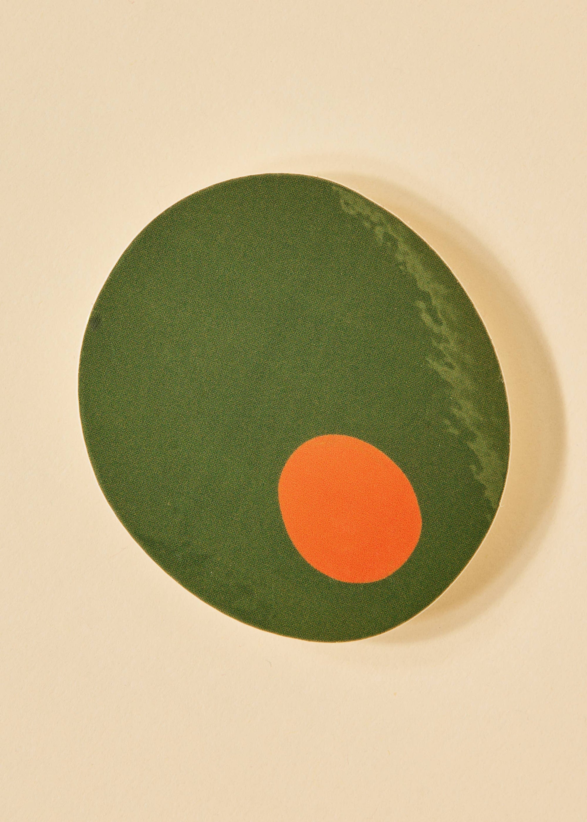 Green olive with an orange dot on a beige background
