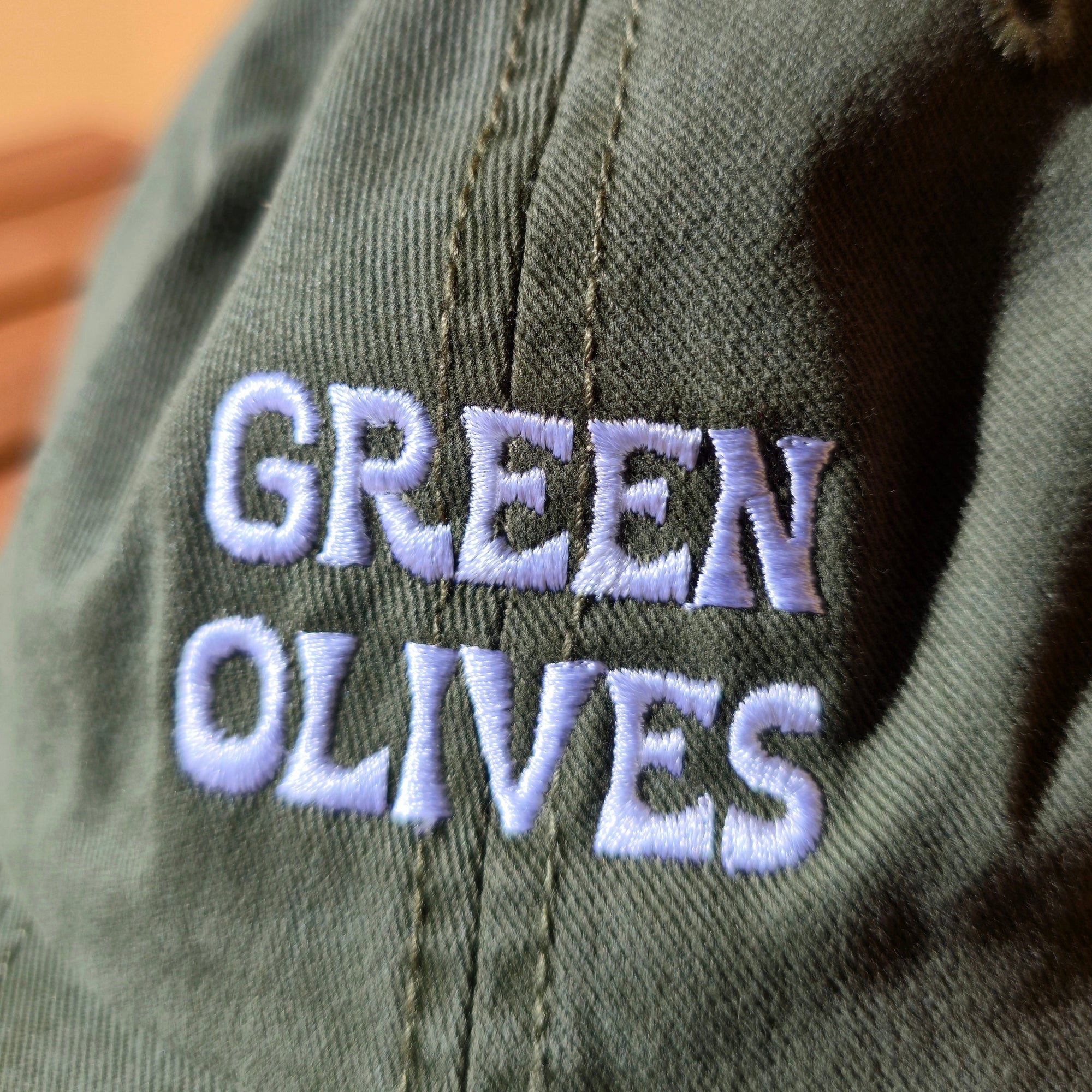 Green cap with 'GREEN OLIVES' embroidered on it against a beige background