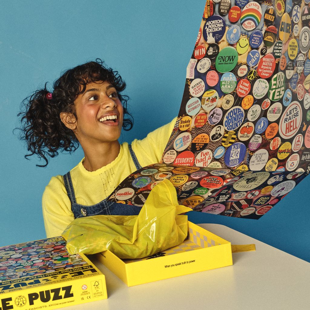 Person holding a colorful puzzle with stickers against a blue background