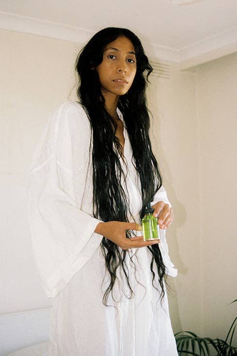 Woman holding a green bottle against a plain background