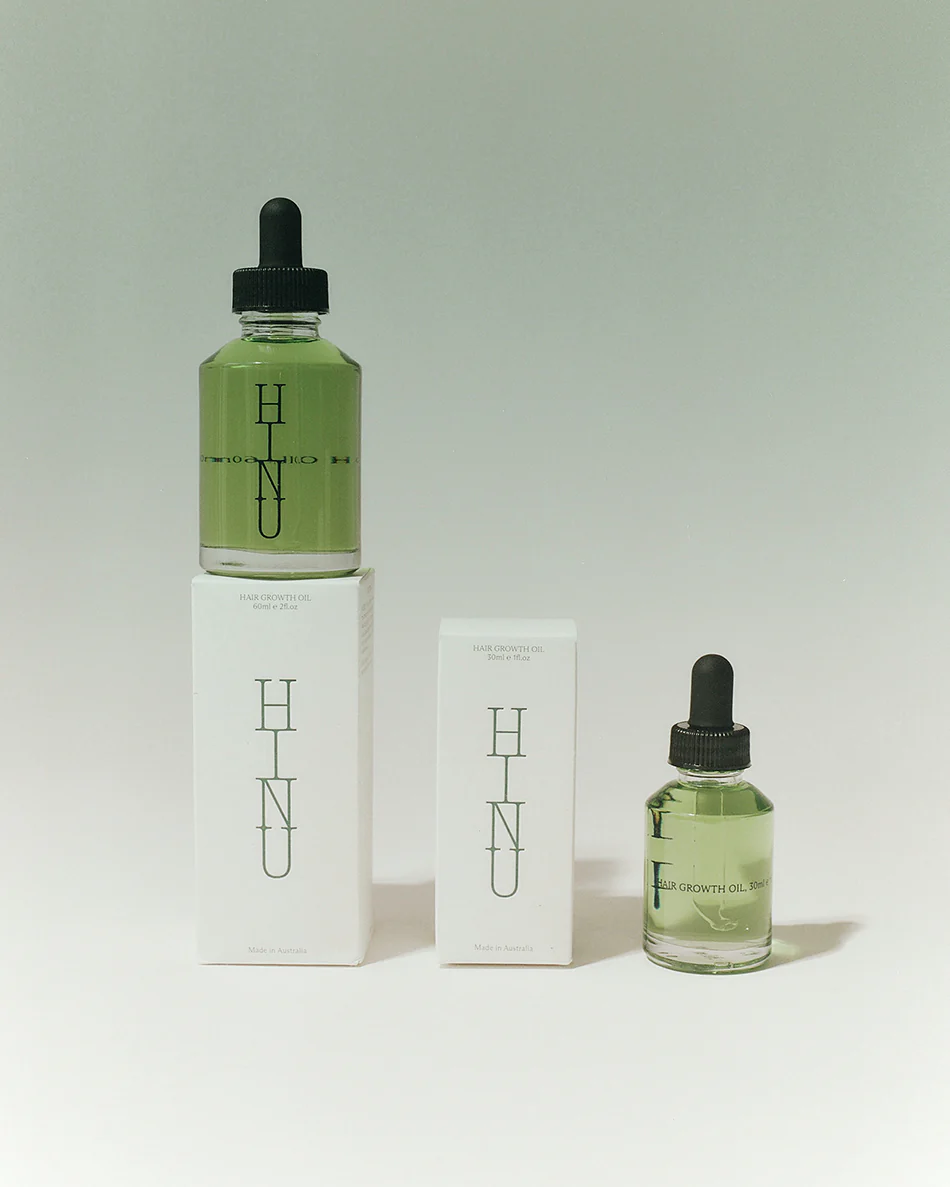 Two bottles of HINU skincare product on a light gray background