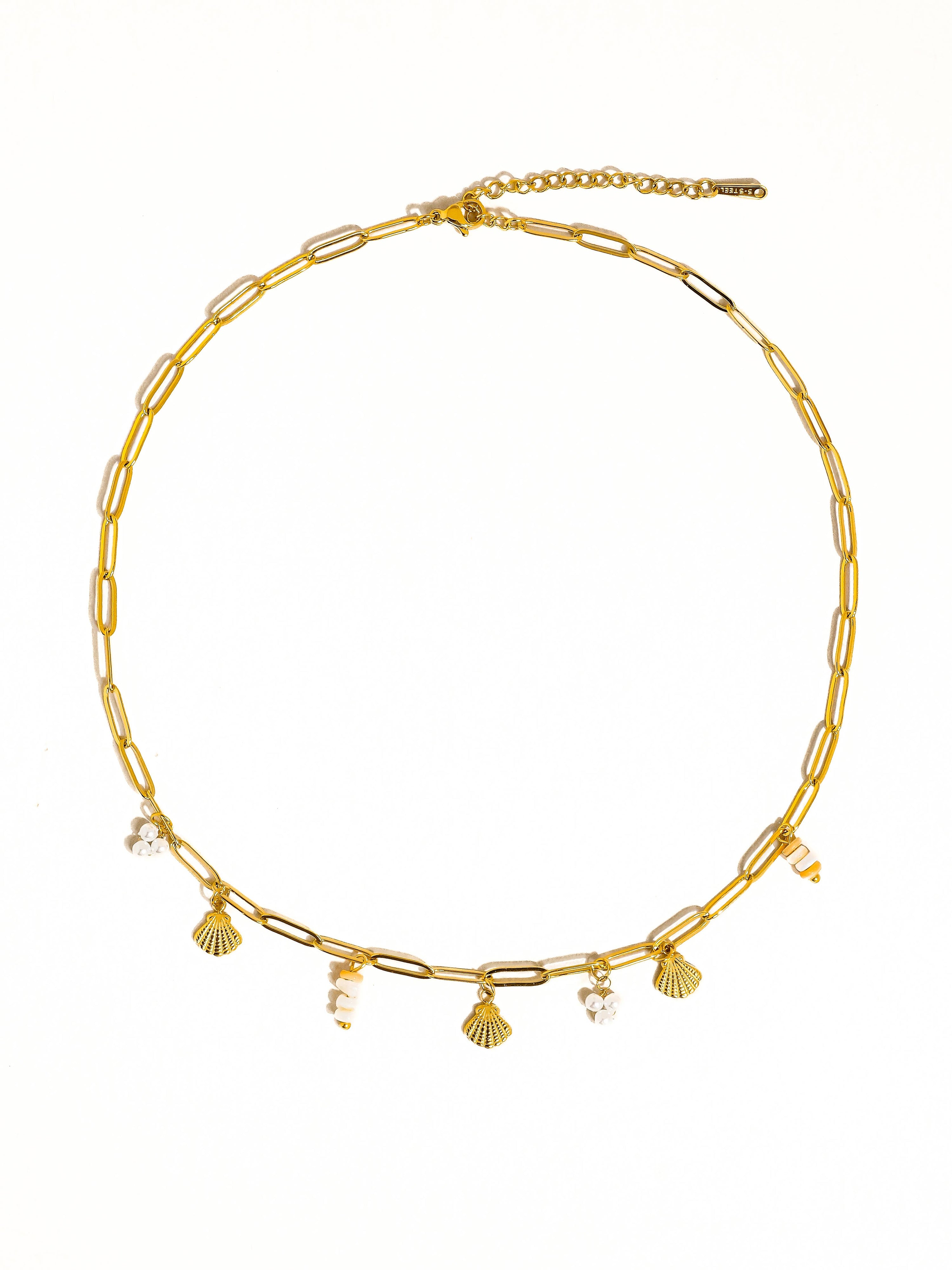 Gold necklace with shell and pearl charms on a white background