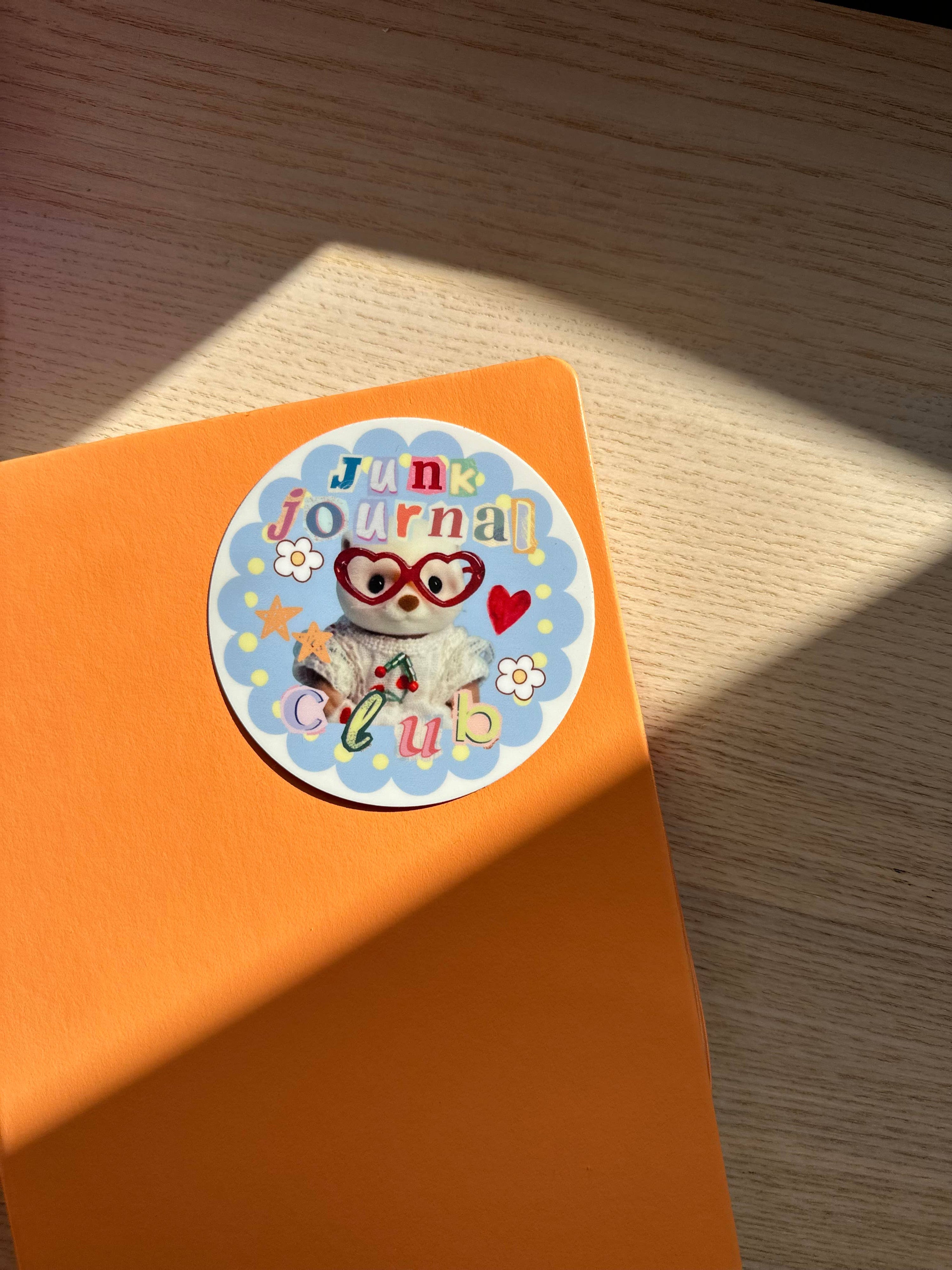 Orange notebook with a sticker featuring an owl and text on a wooden surface