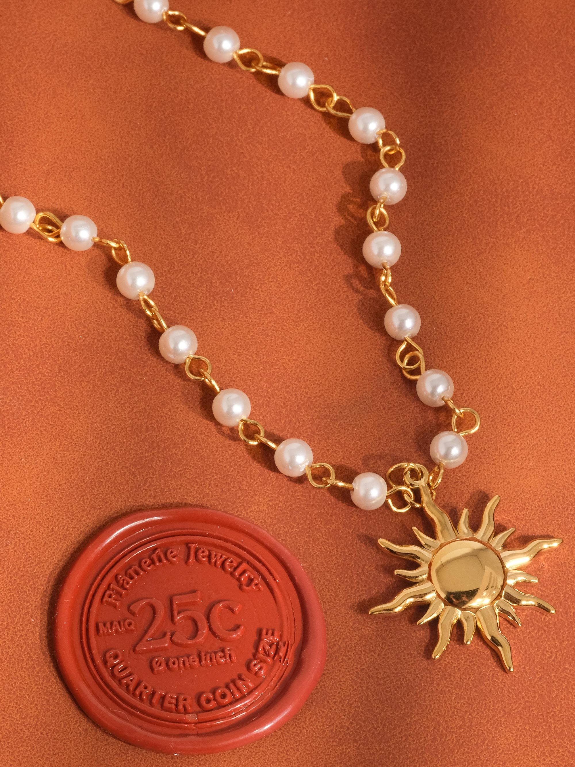 Necklace with pearl beads and sun-shaped gold charm on a brown background with a 25c coin stamp.