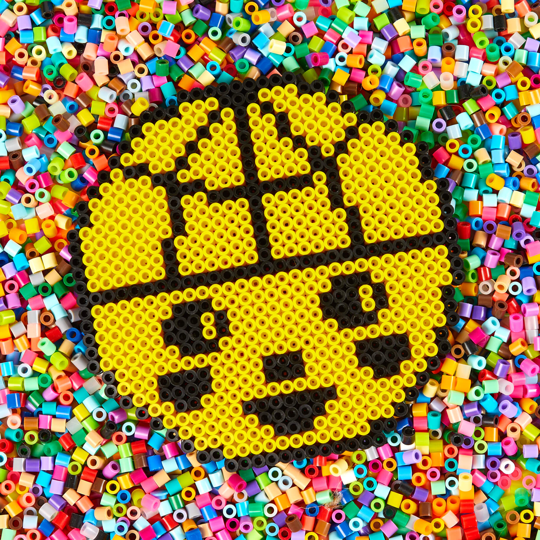 Colorful beaded pattern of a smiley face on a background of multicolored beads