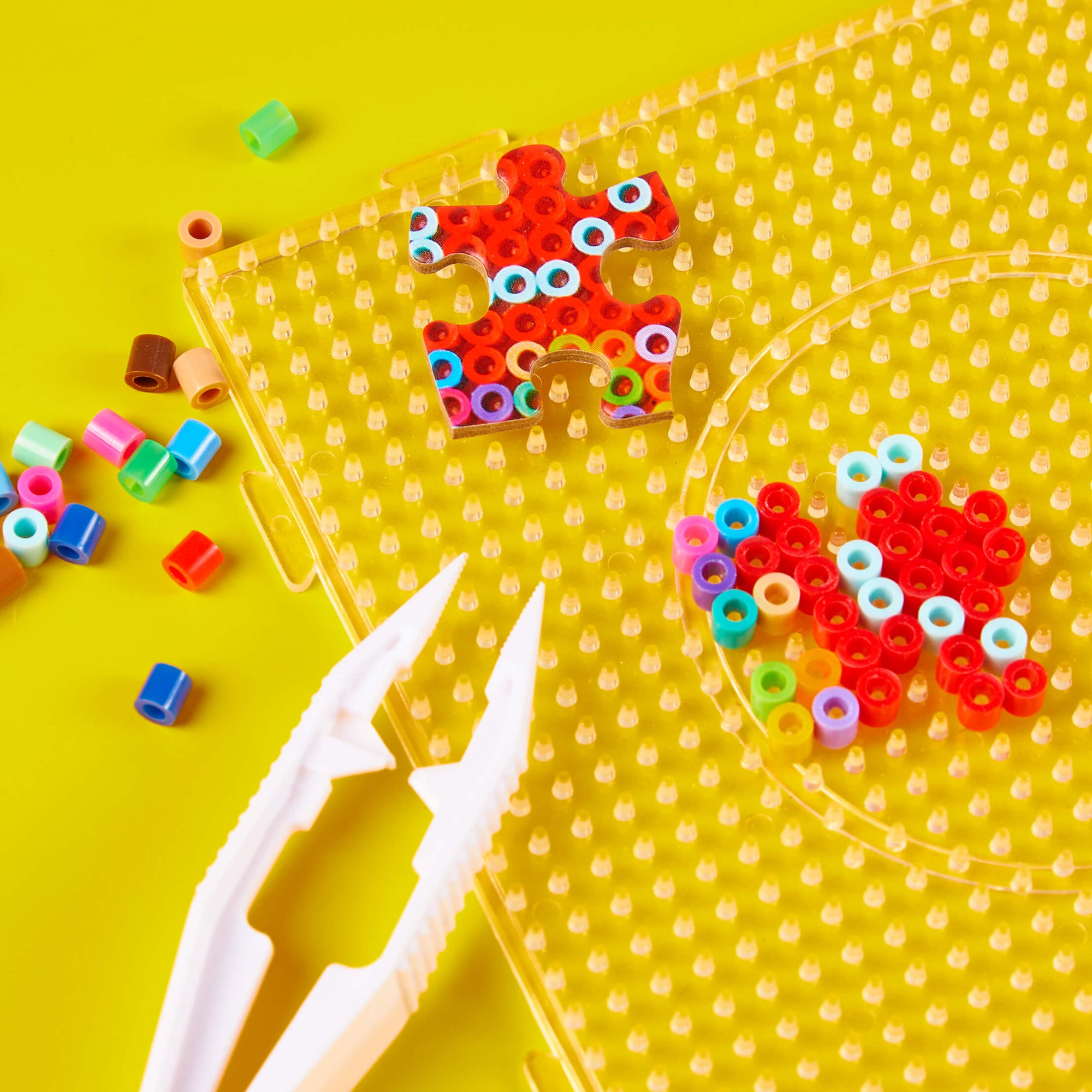 Colorful building block puzzle on a yellow pegboard with scissors on a yellow background