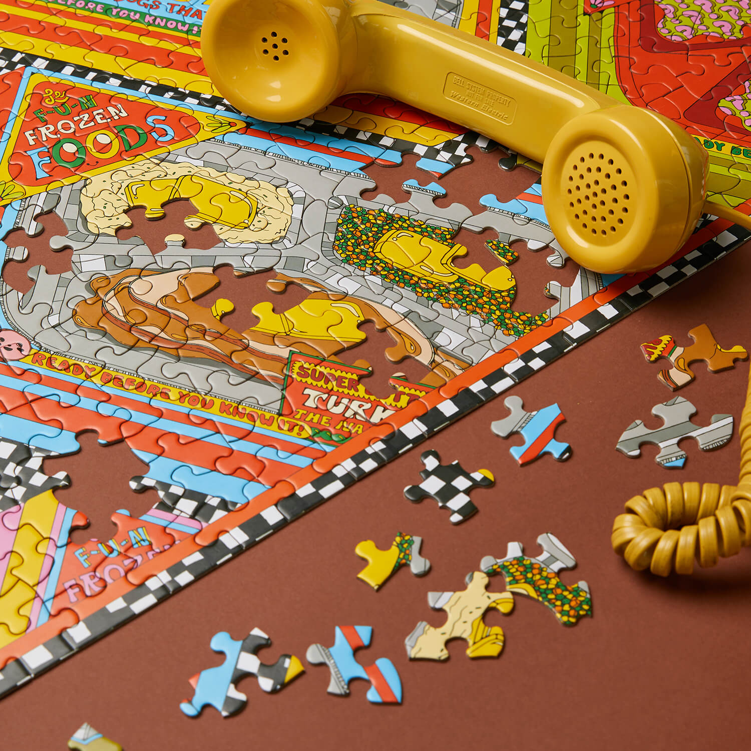 Colorful puzzle with a yellow toy phone on a brown surface