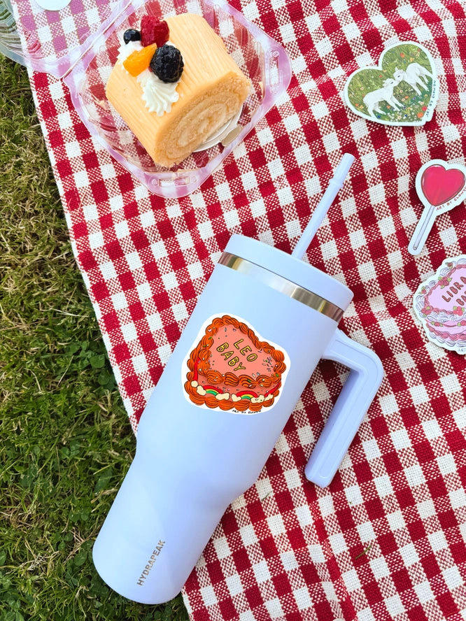 White insulated tumbler with a design on a red and white checkered blanket with a cake and lollipops.