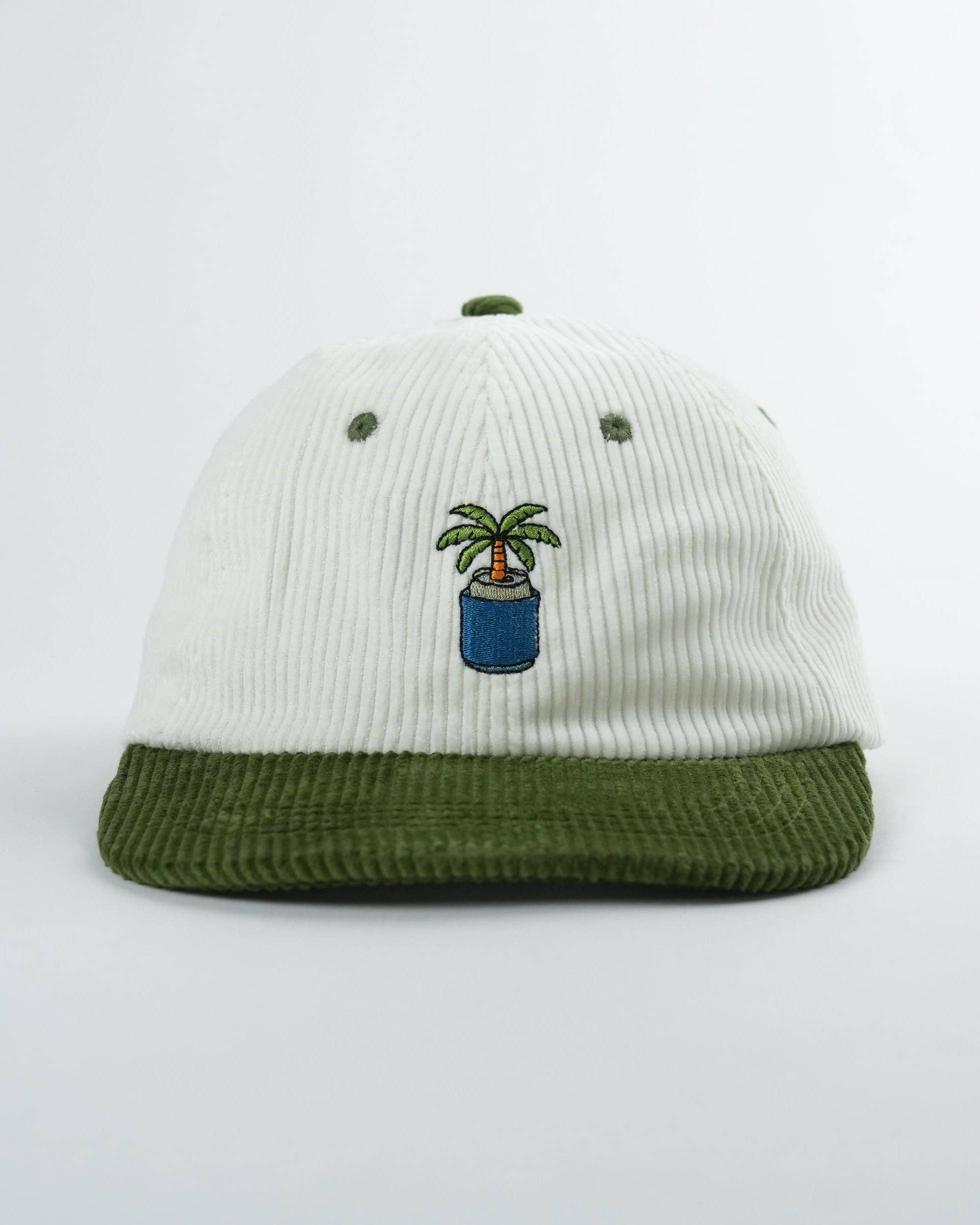 White and green cap with a palm tree design on a light gray background