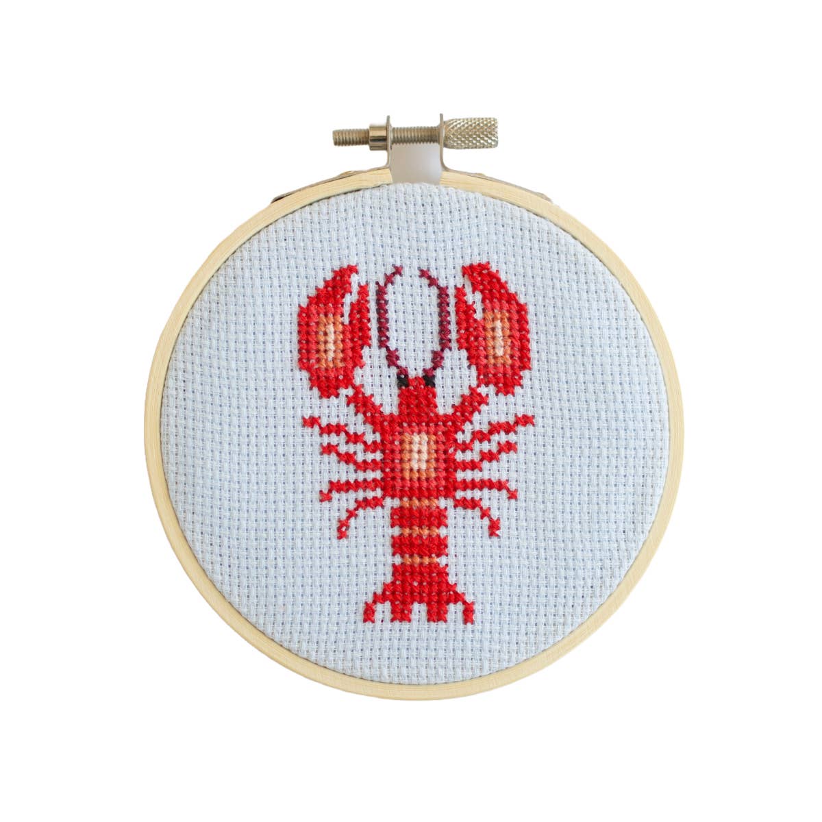 Cross-stitched lobster design on a white background with a wooden hoop.