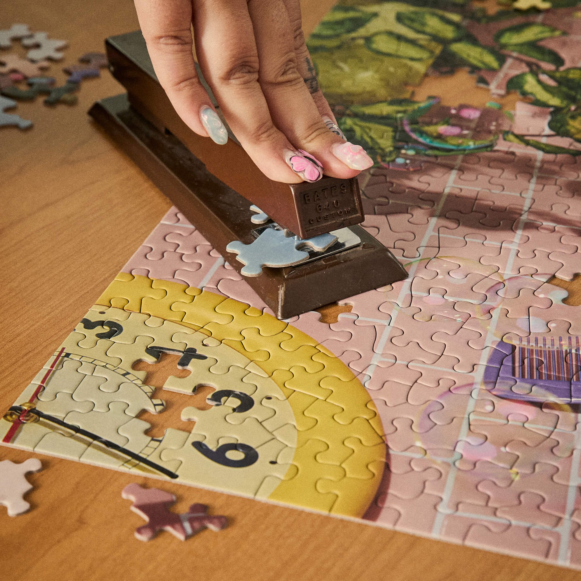Two people assembling the Le Puzz ME-ow Time puzzle on a desk with the yellow puzzle box and retro telephone prop