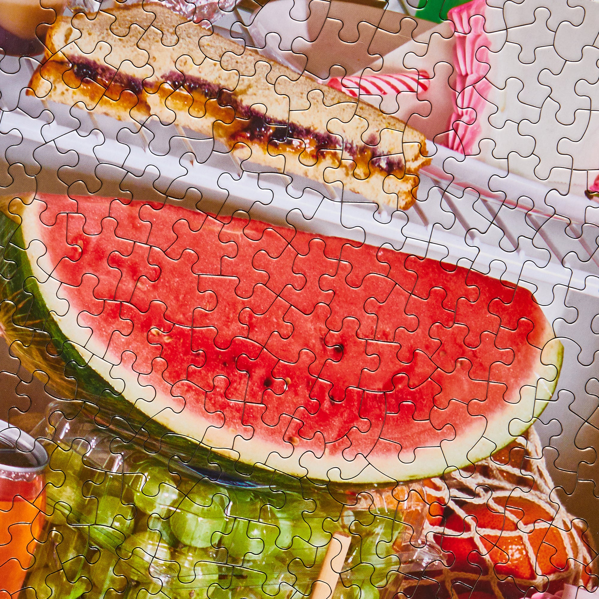 Close-up of Le Puzz Midnight Snack puzzle pieces showing a watermelon slice and colourful fridge snacks