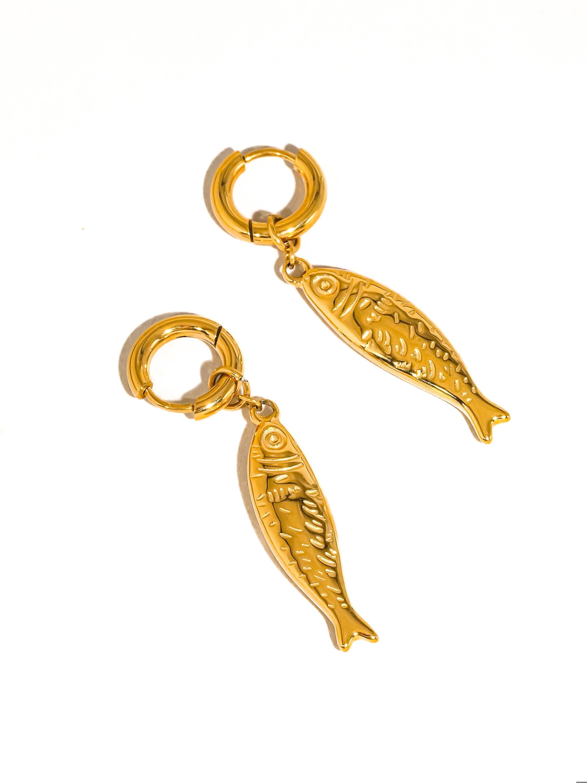 Gold fish-shaped charms on a white background