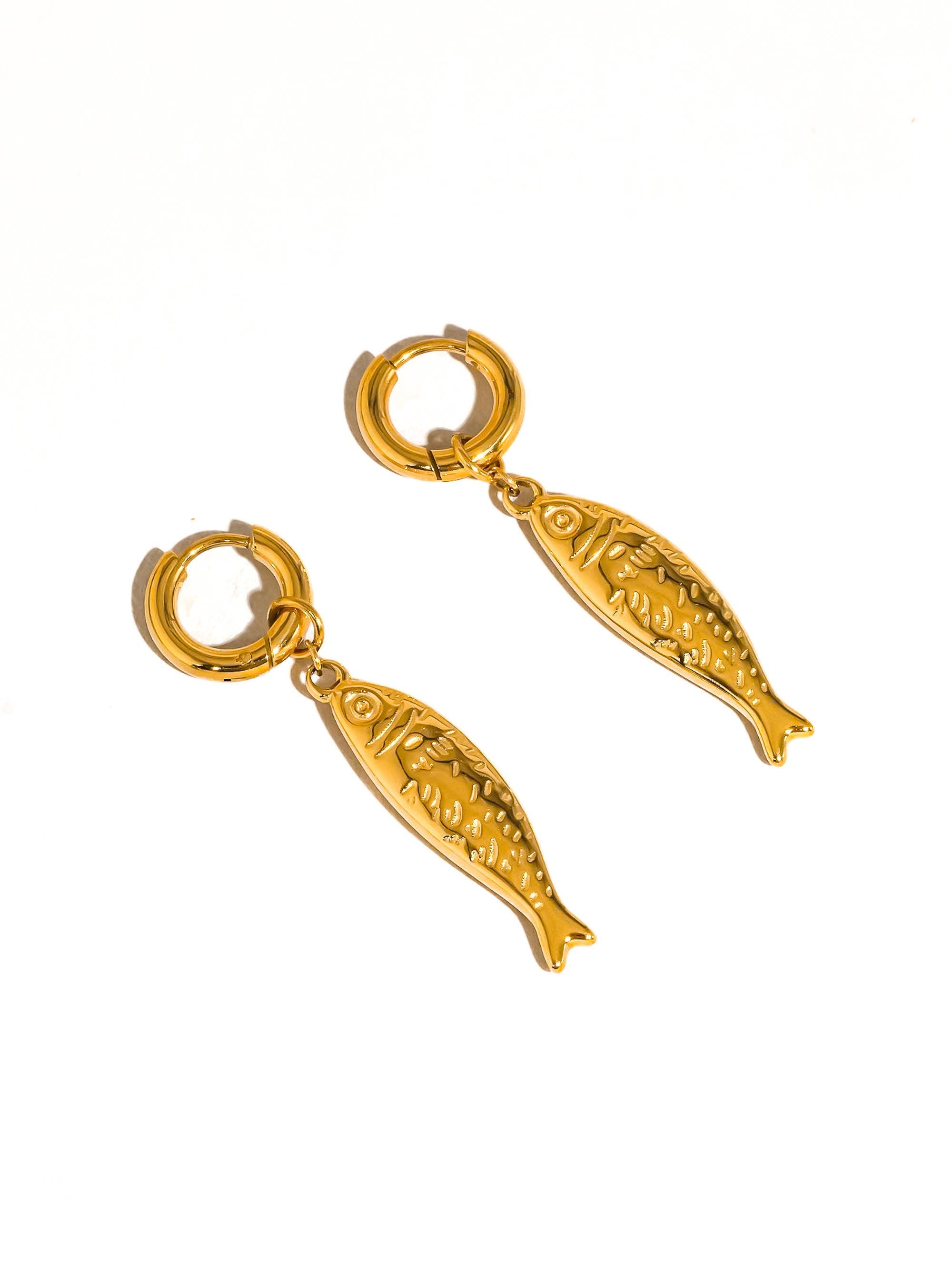 Gold fish-shaped earrings on a white background