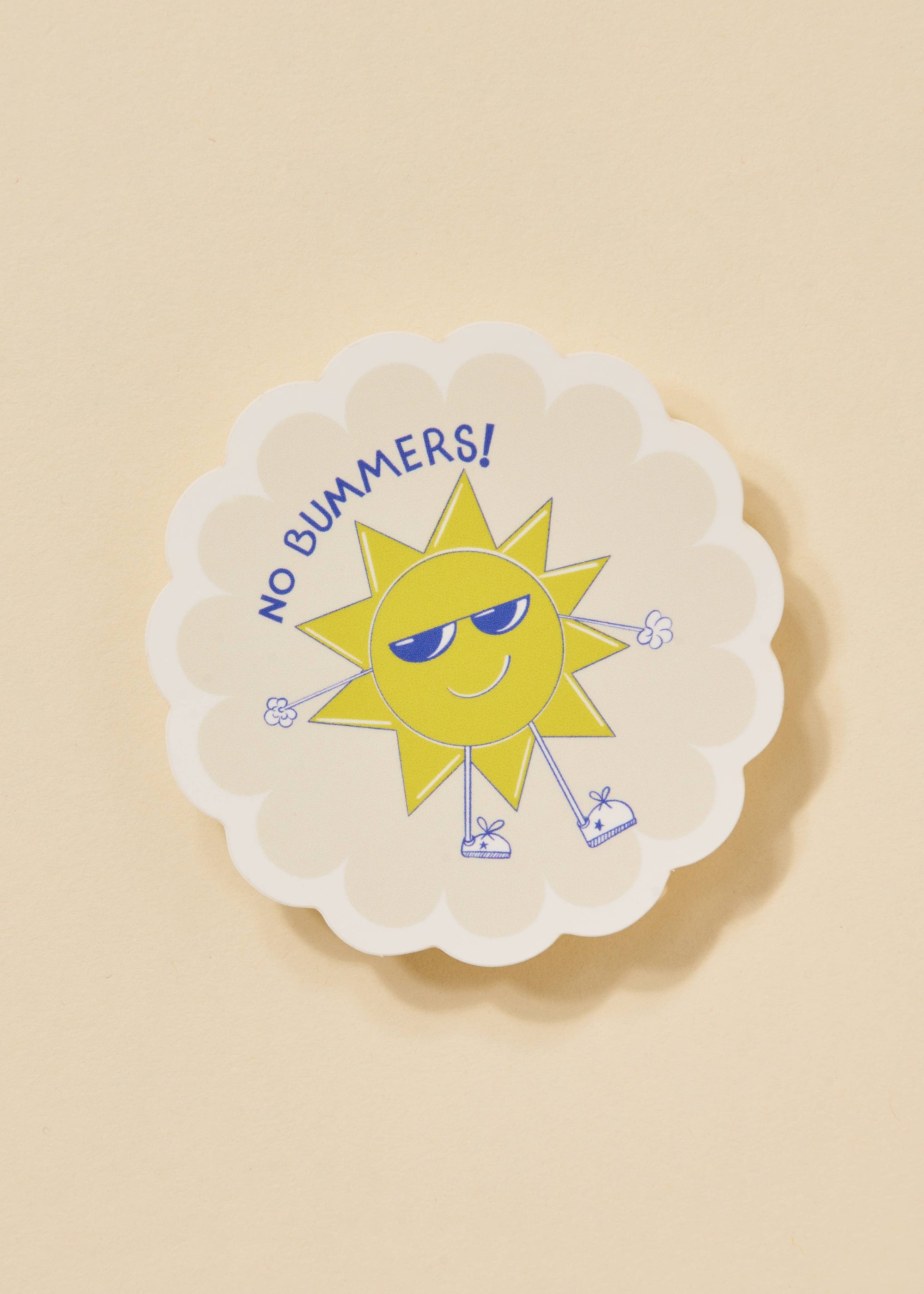 Circular sticker with a sun character and 'No Bummers!' text on a beige background