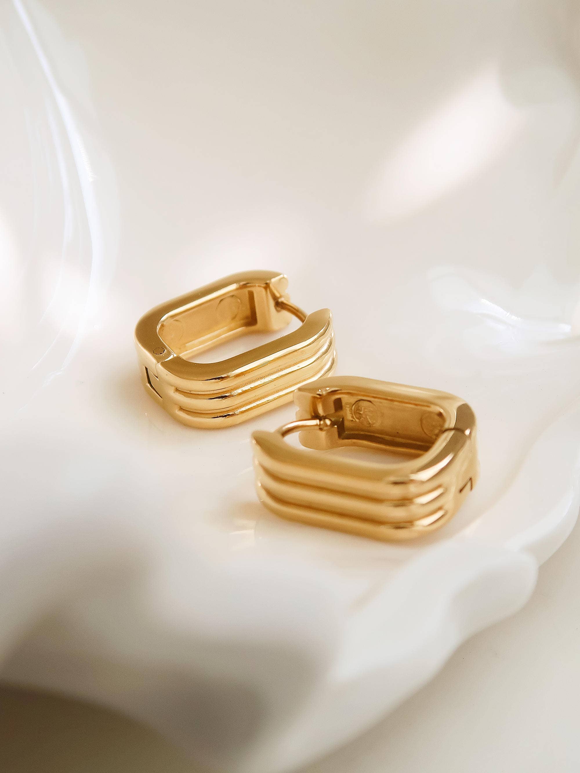Gold hoop earrings on a white fabric background