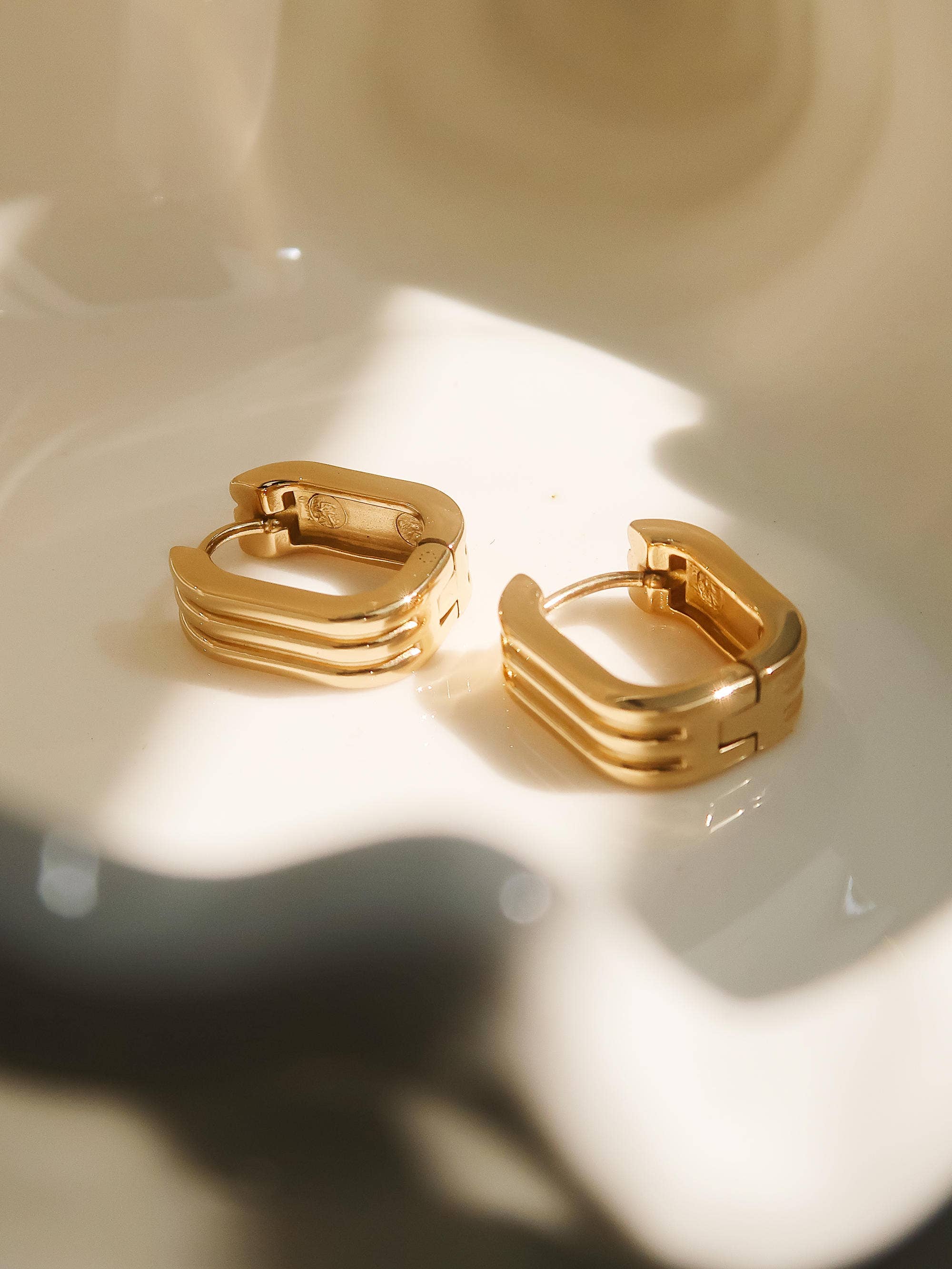 Gold hoop earrings on a textured beige surface