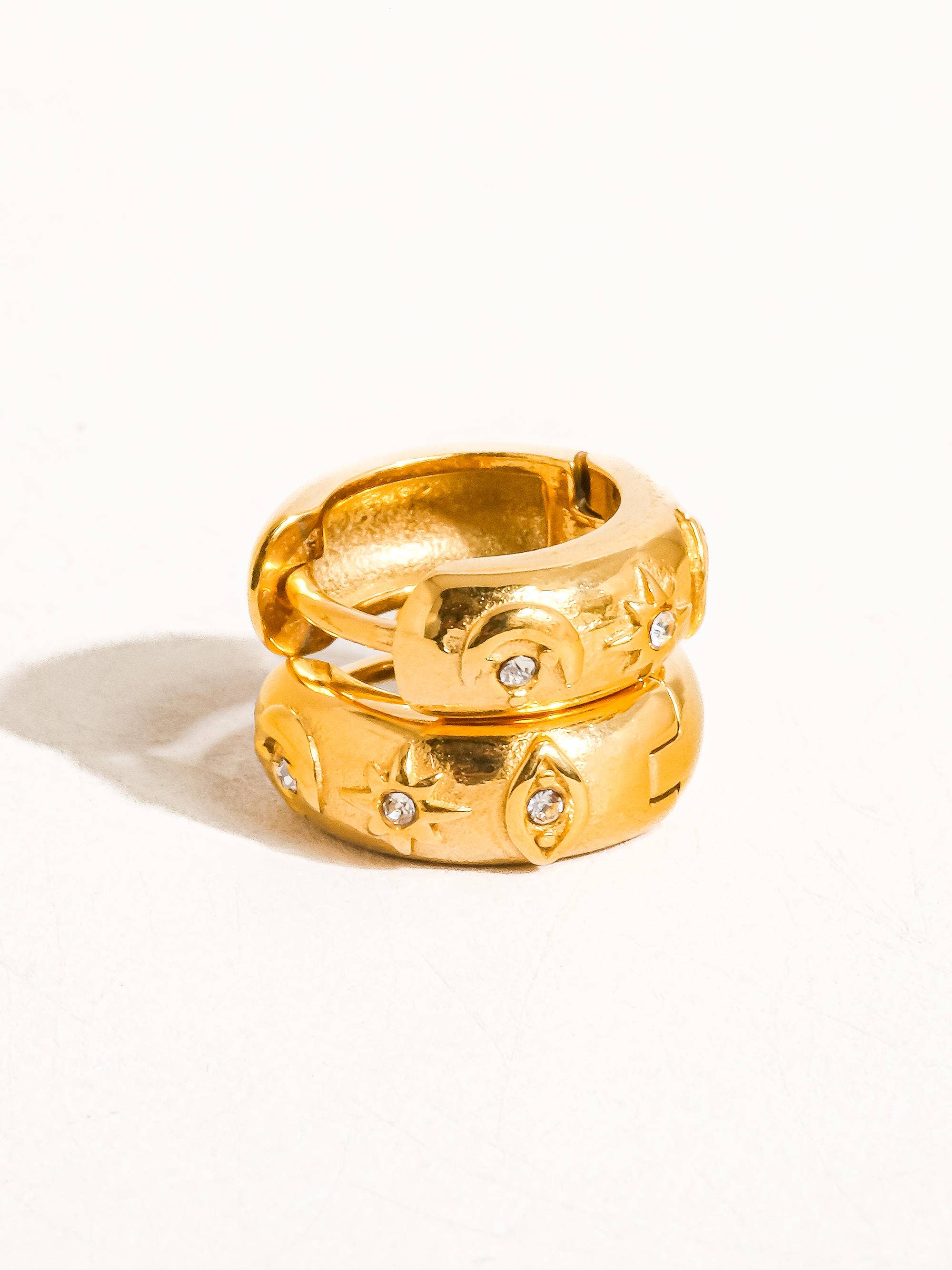Two gold rings with embedded stones on a white background