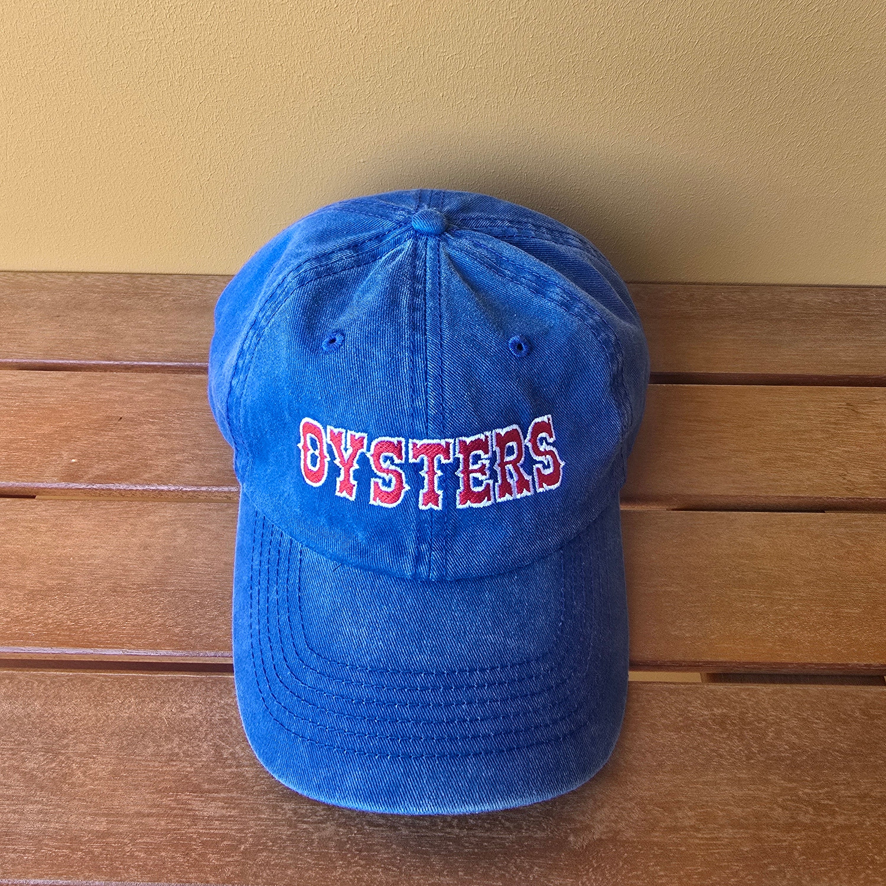 Blue cap with 'OYSTERS' text on a wooden surface