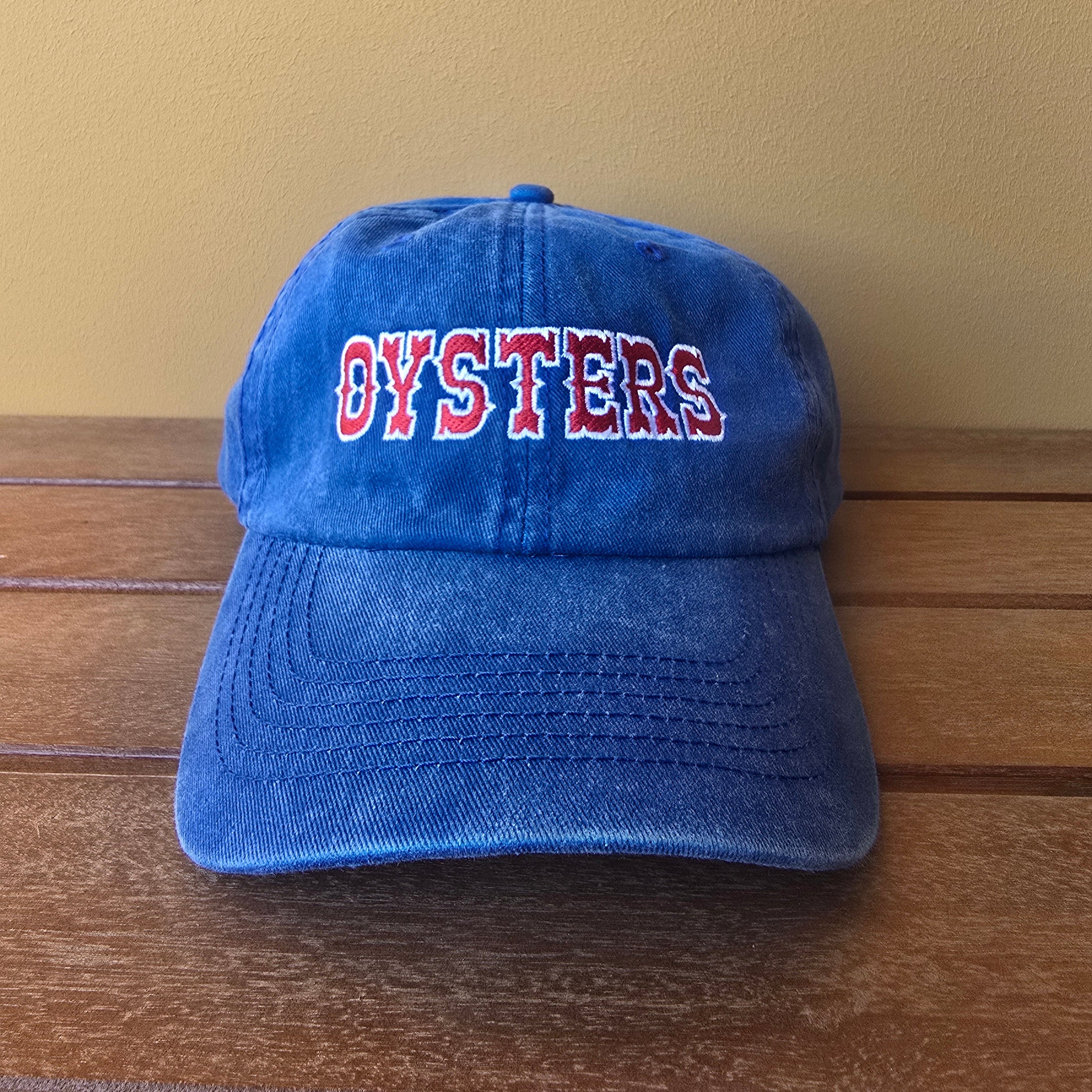 Blue cap with 'OYSTERS' text on a wooden surface