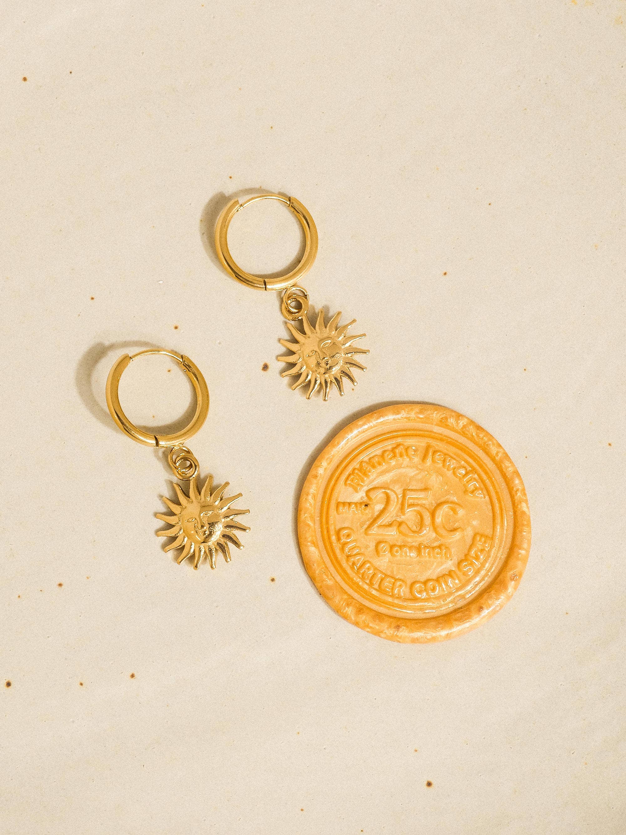 Gold coin and sun-shaped keychain on a beige background