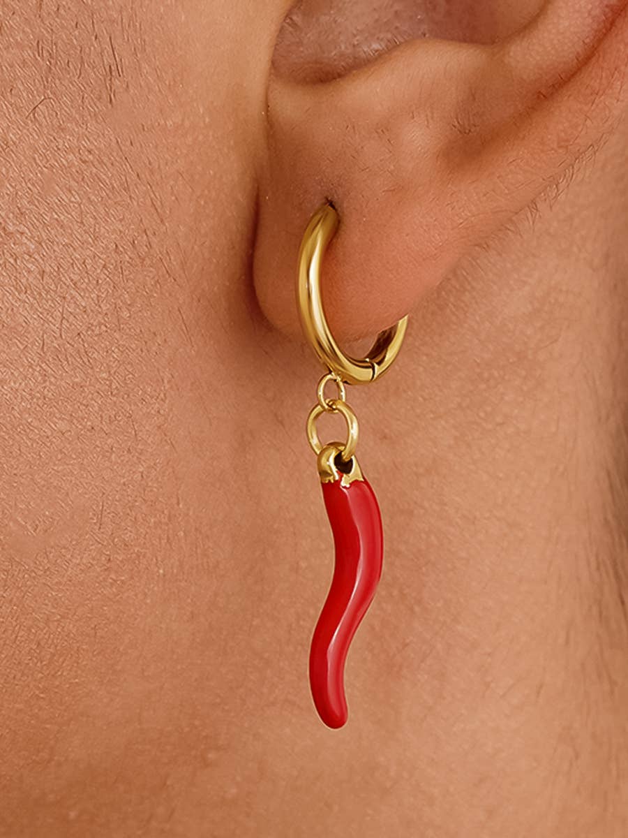Gold earring with a red chili pepper charm on a person's ear.