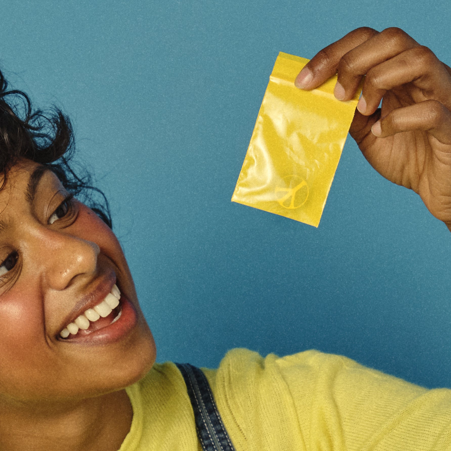 Person holding a yellow packet against a blue background