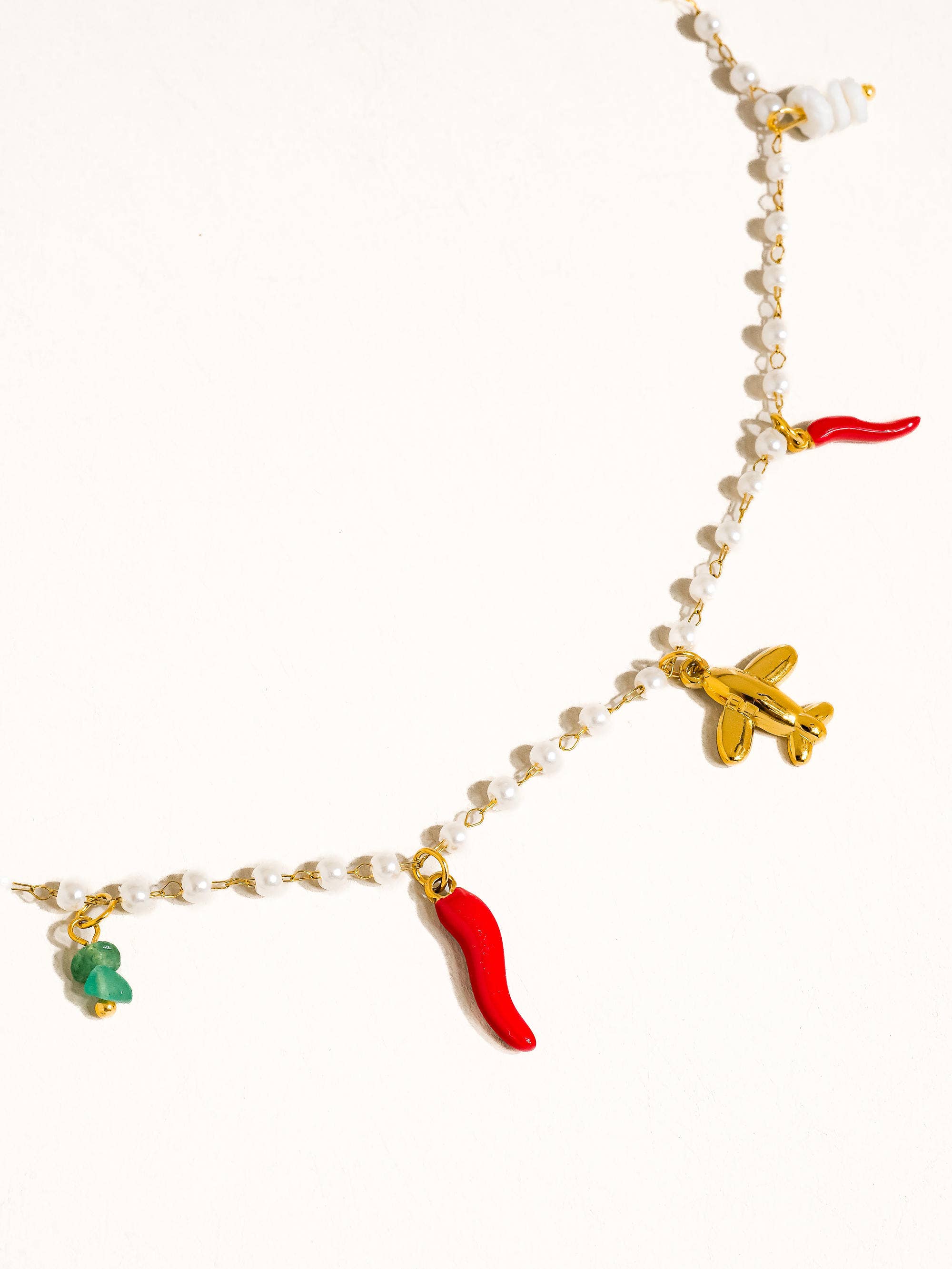 Bracelet with various charms including a plane, chili pepper, and green object on a white background