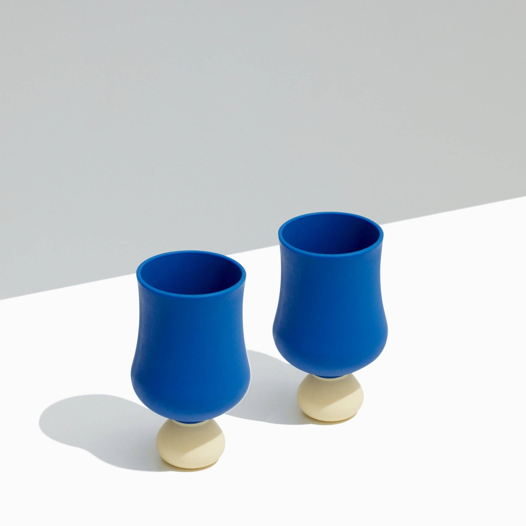 Two blue cups with beige bases on a light gray background