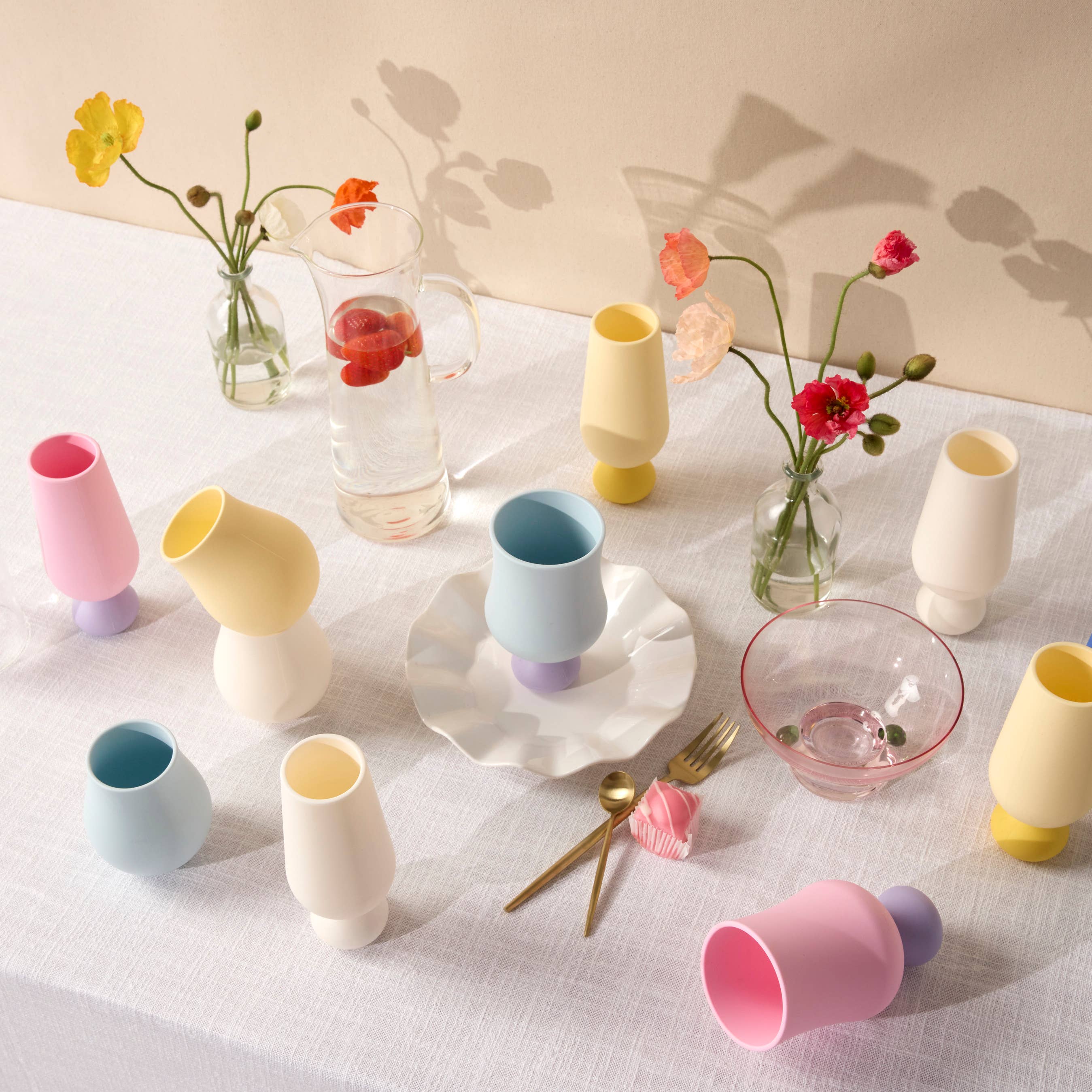 Colorful ceramic tableware on a light surface with flowers and cutlery.